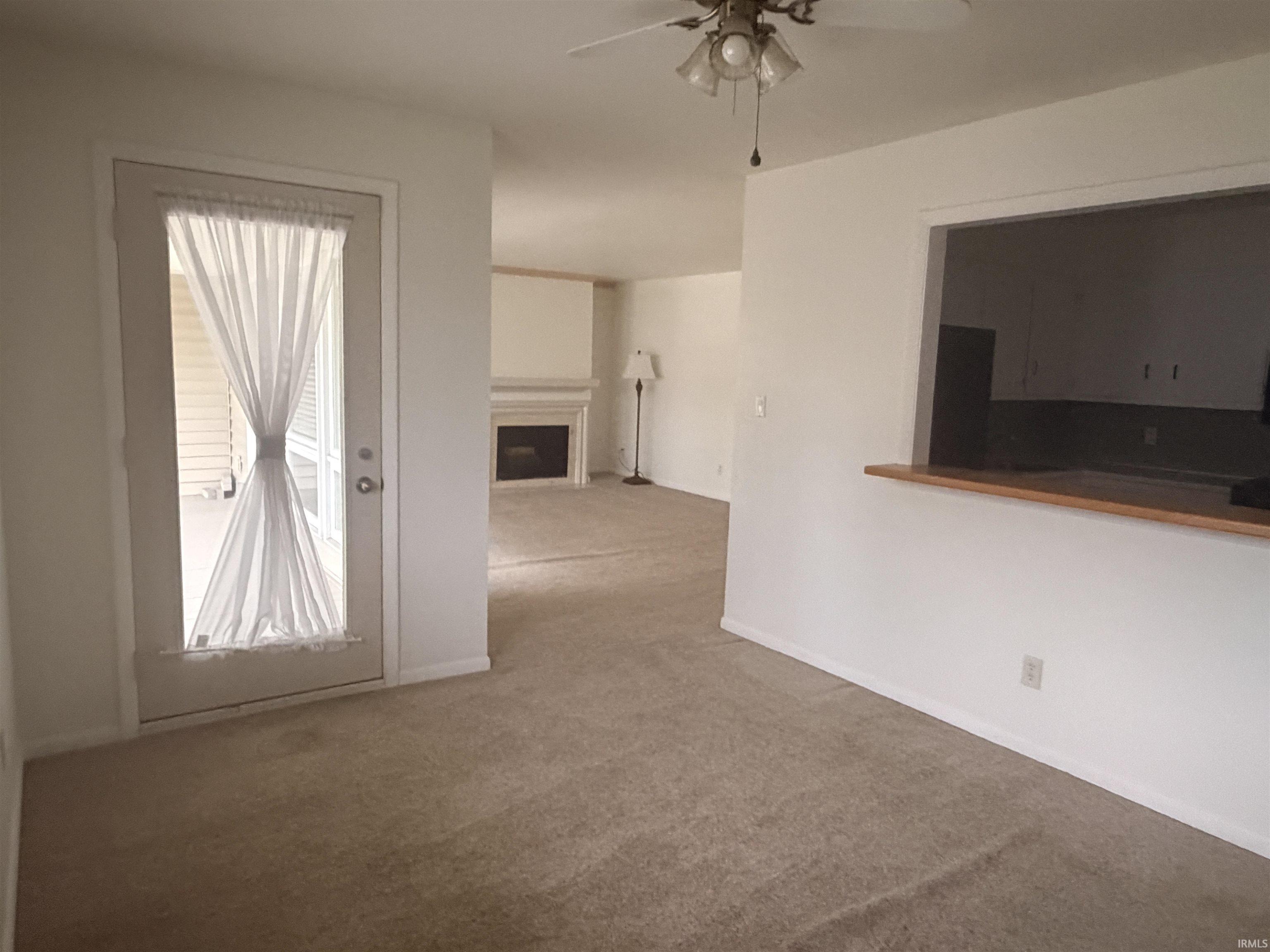 Carpeting throughout, white painted walls, ceiling fan, and a fireplace with a mantel