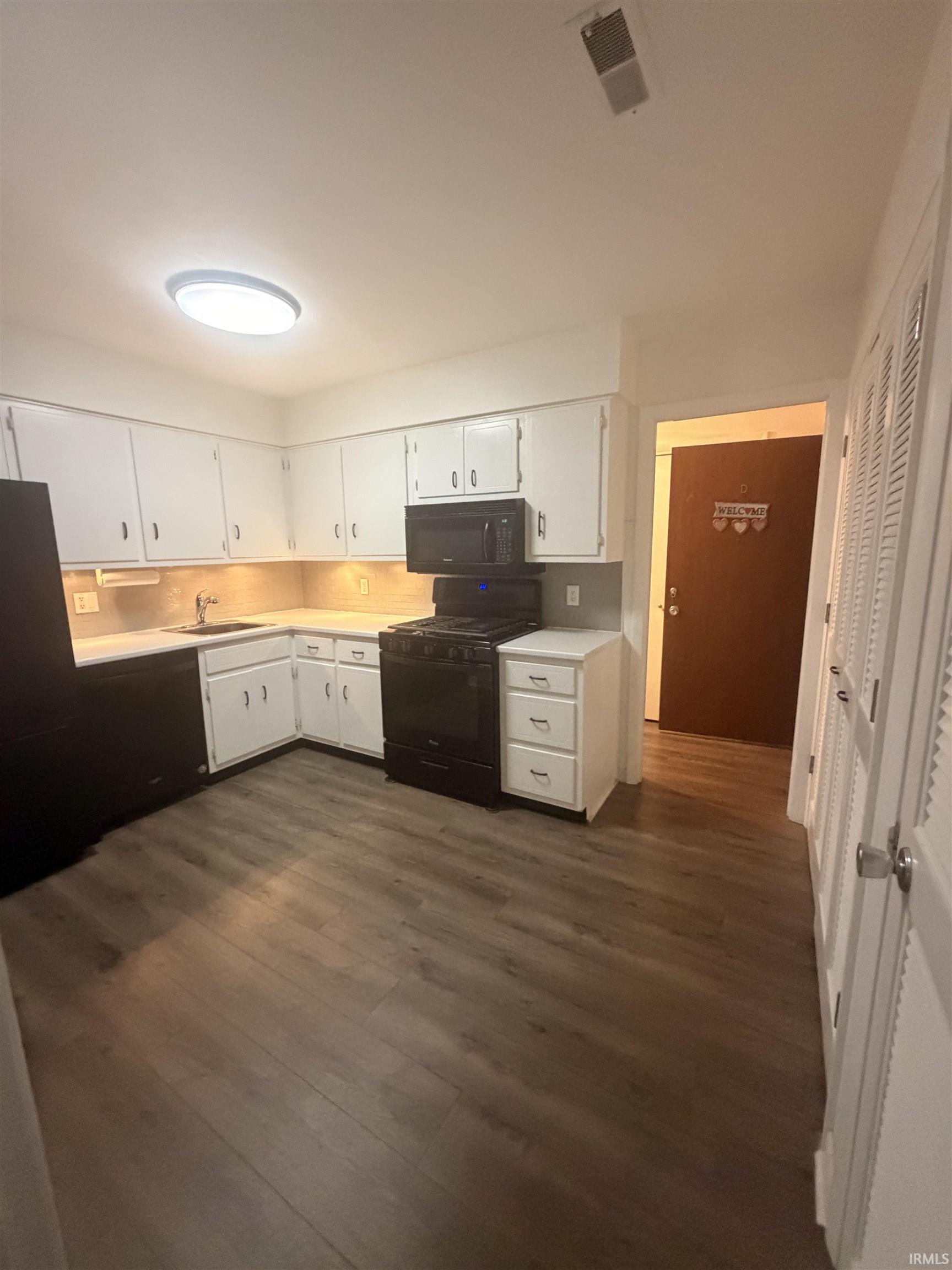 Kitchen featuring white cabinetry, black appliances, wood-finish flooring, and recessed lighting