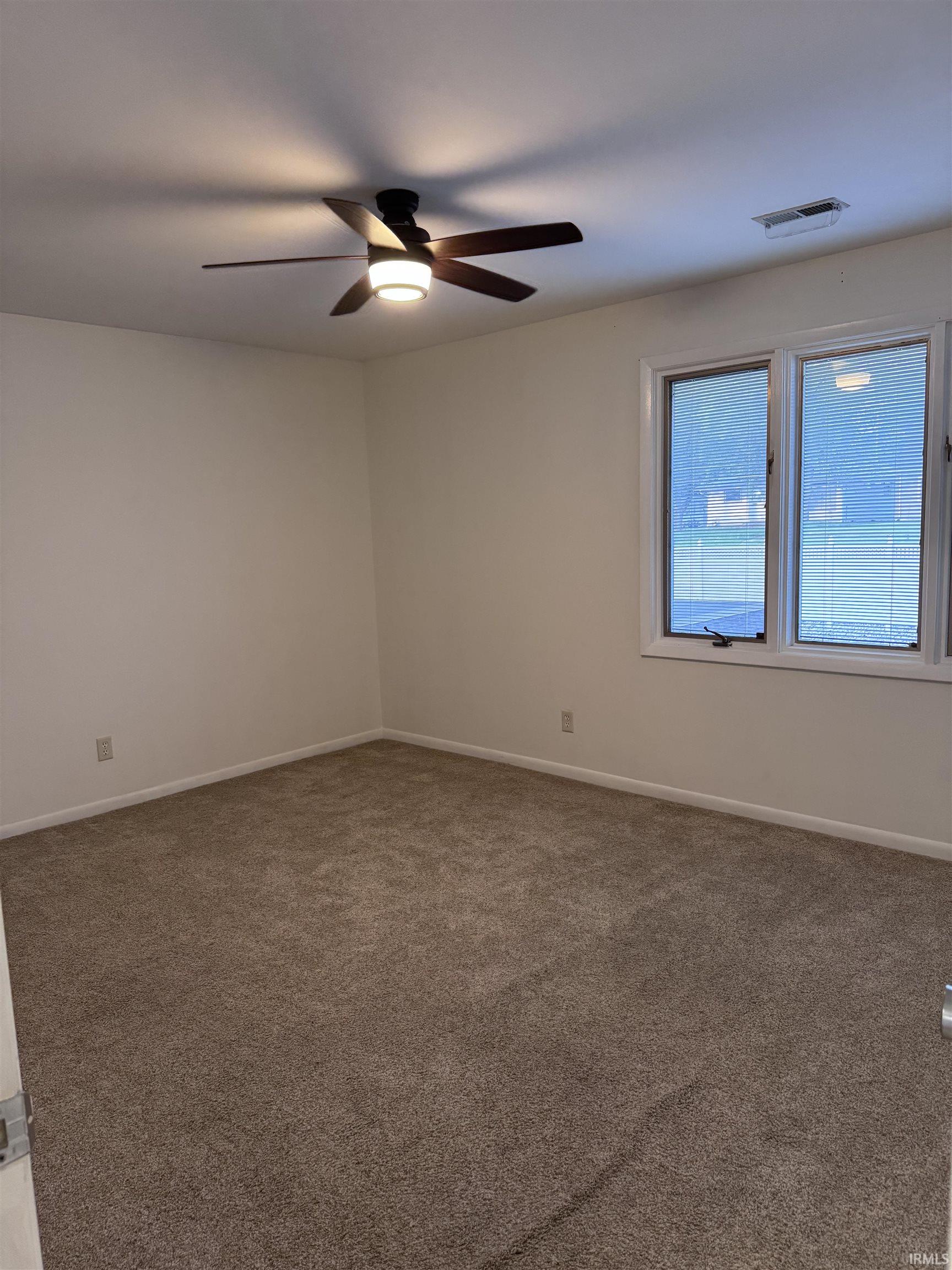 Plush carpet flooring, white walls, and a ceiling fan with integrated lighting