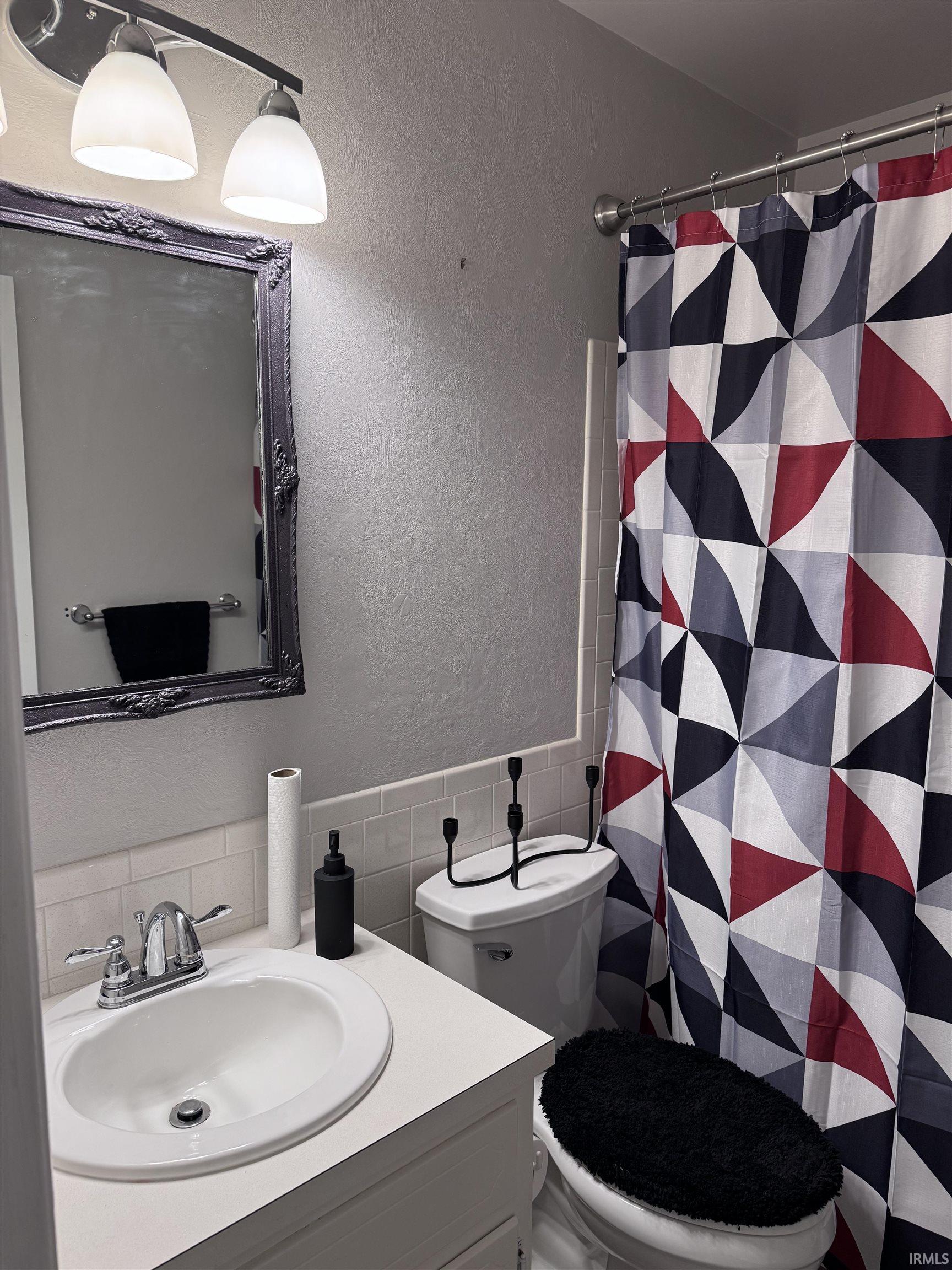 Single-sink vanity with chrome-finish faucet, framed mirror, and two-light vanity fixture