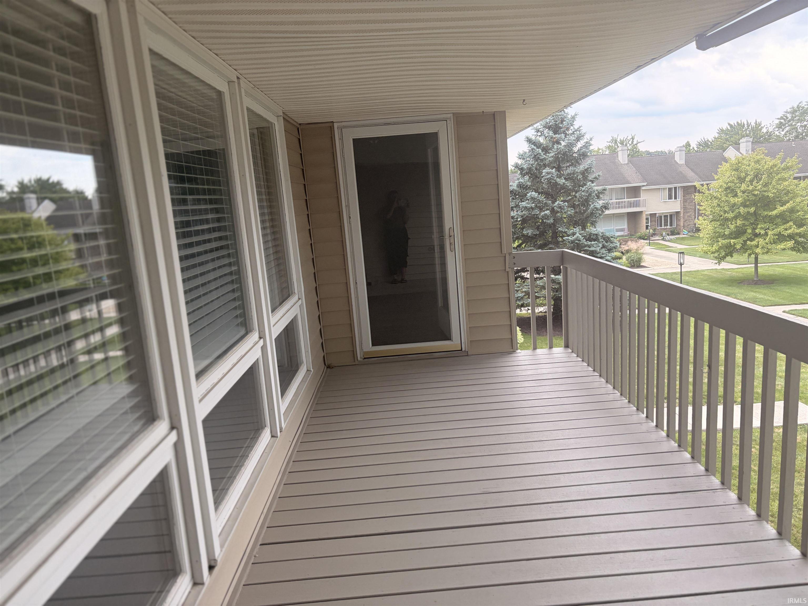 Private balcony with plank decking, white railings, and vinyl siding