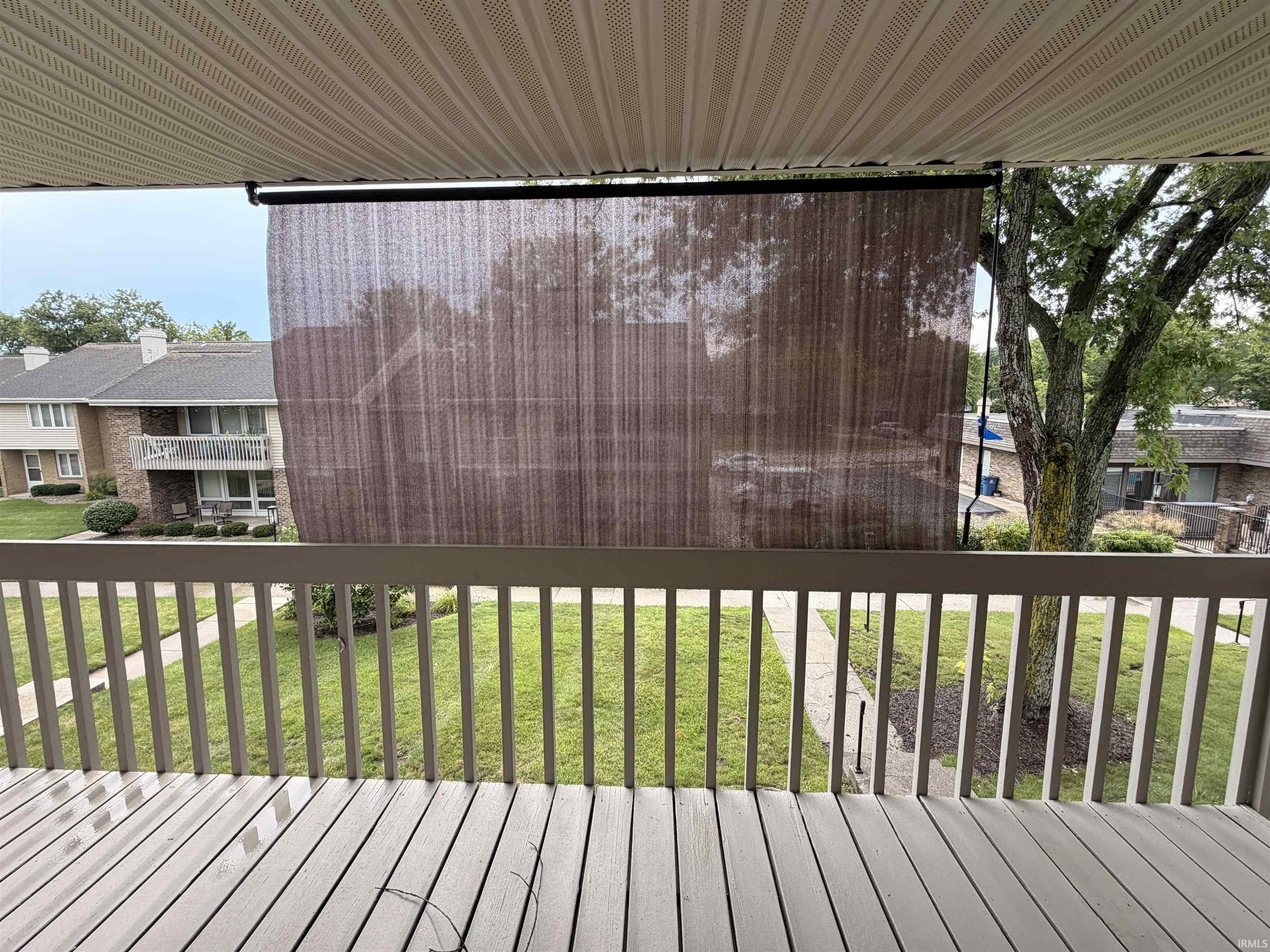 Balcony with slatted flooring, white railing, and a pull-down privacy screen