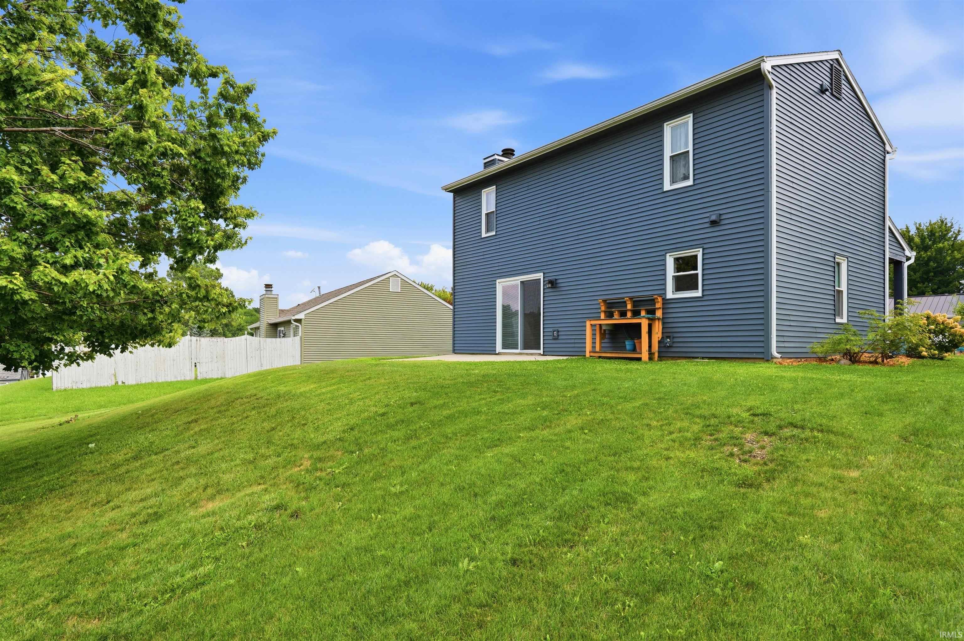 Expansive green lawn with a two-story home featuring blue siding and a sliding glass door