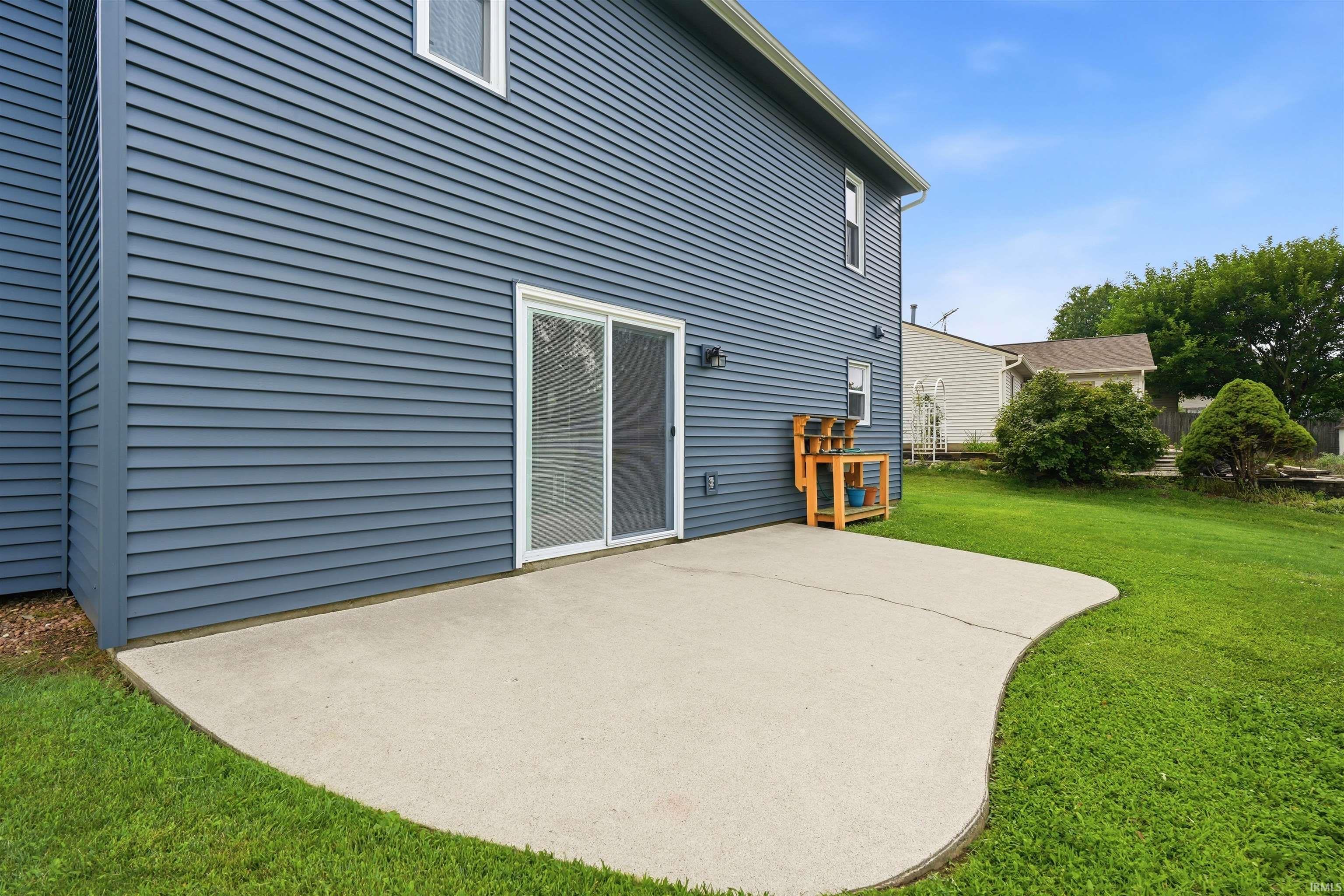 Exterior featuring horizontal siding, a sliding glass door, and a curved concrete patio