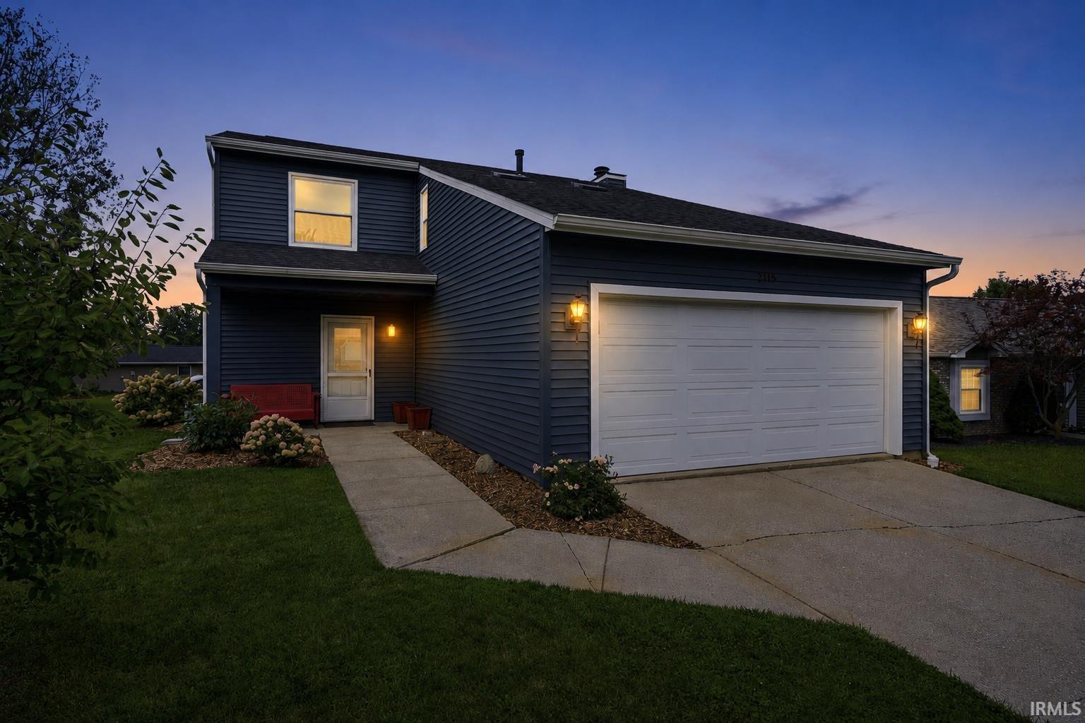 Two-story exterior with dark siding, a concrete driveway, and an attached two-car garage
