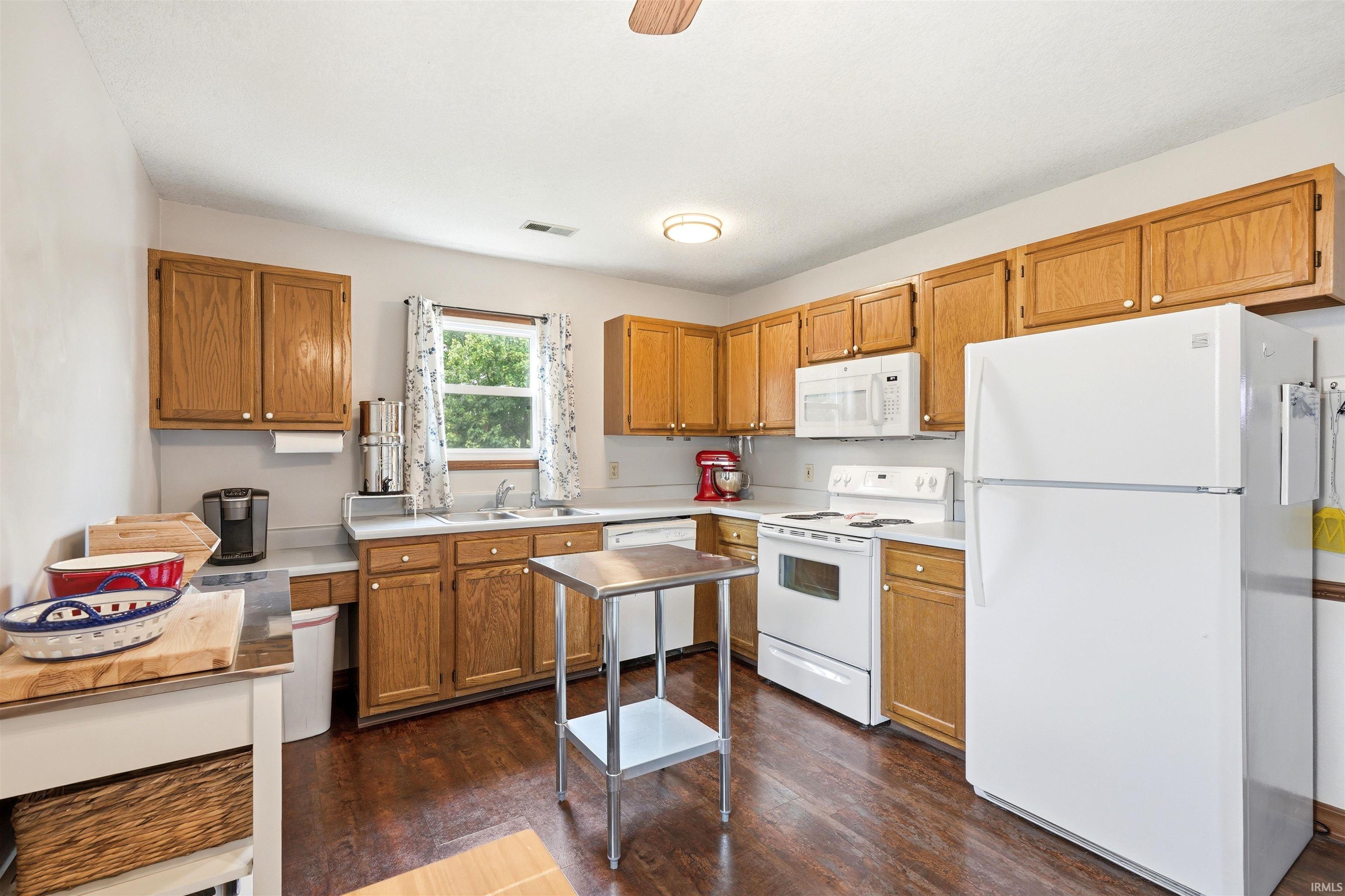 Kitchen featuring wood-finish flooring, wood cabinetry, white appliances, and a window with natural light