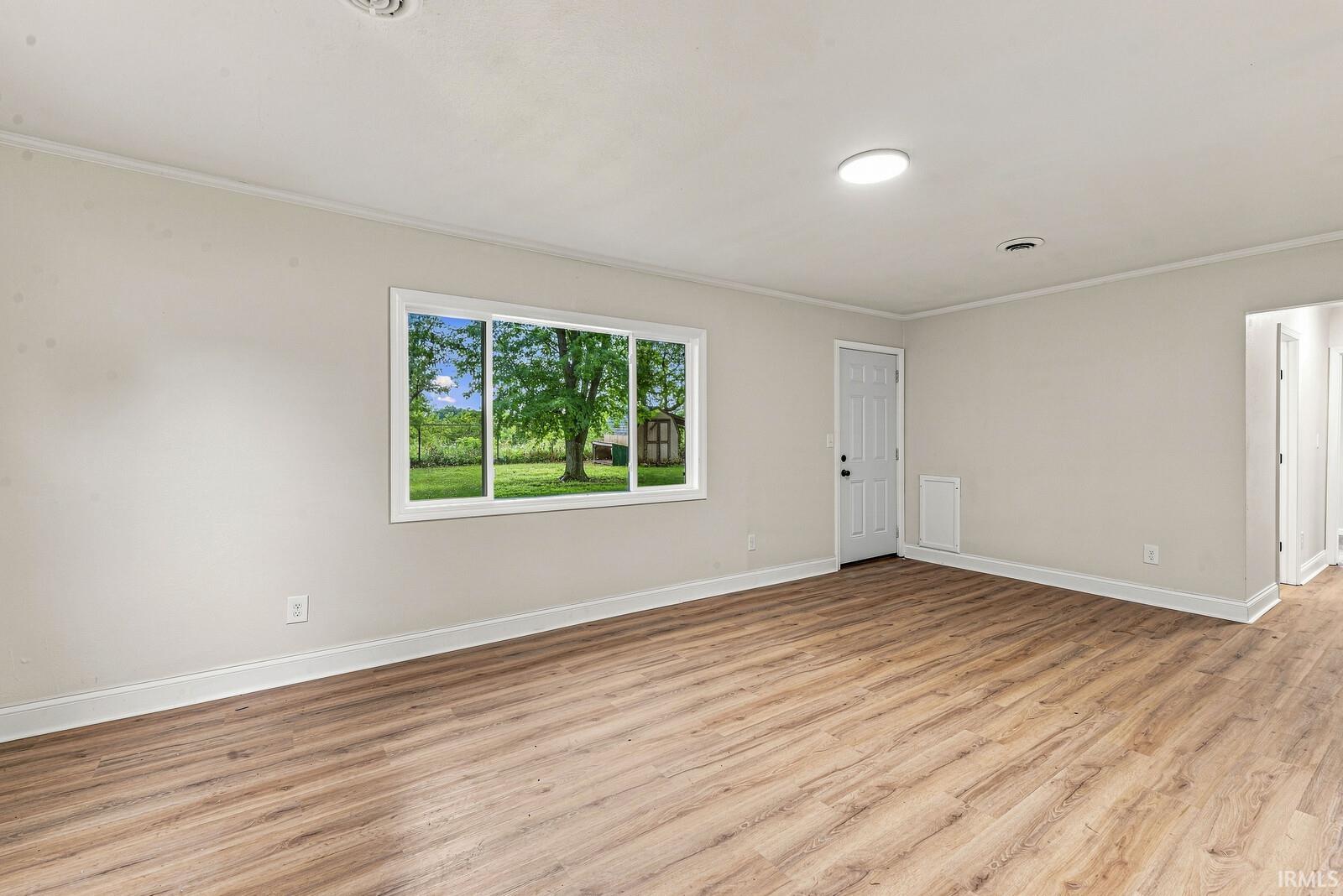 Light-toned walls, wood-finish flooring, white trim throughout, and a white paneled door