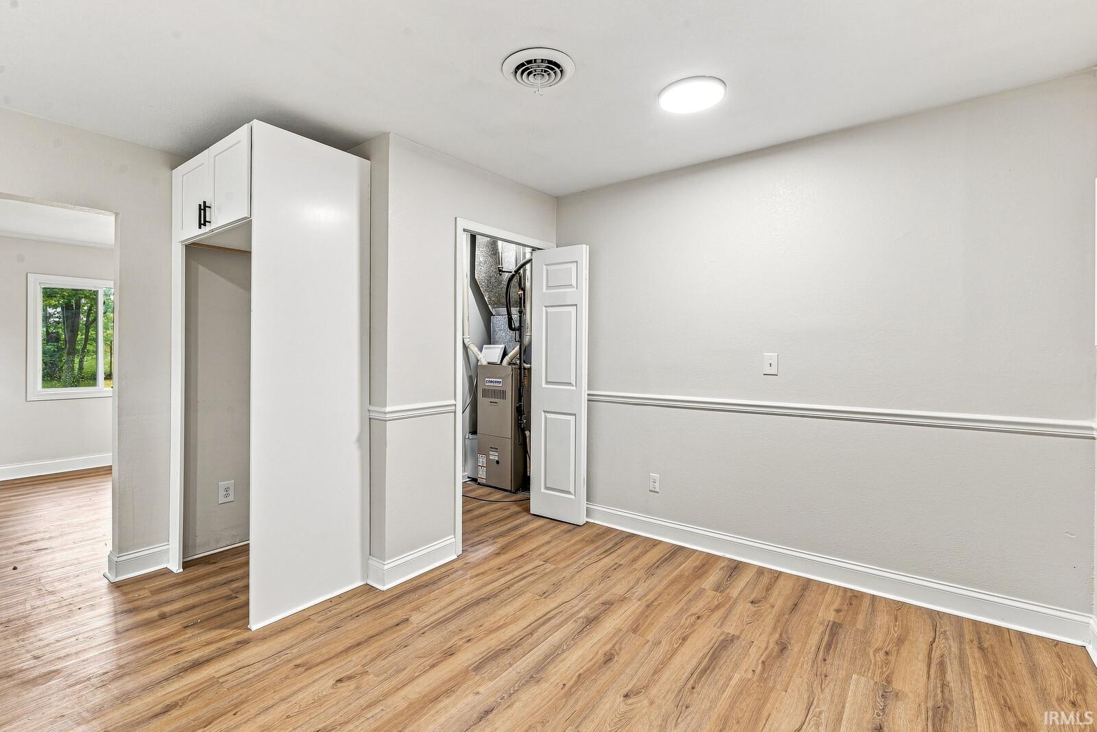 Wood-finish flooring, built-in cabinetry with black hardware, chair rail molding, and a recessed ceiling light