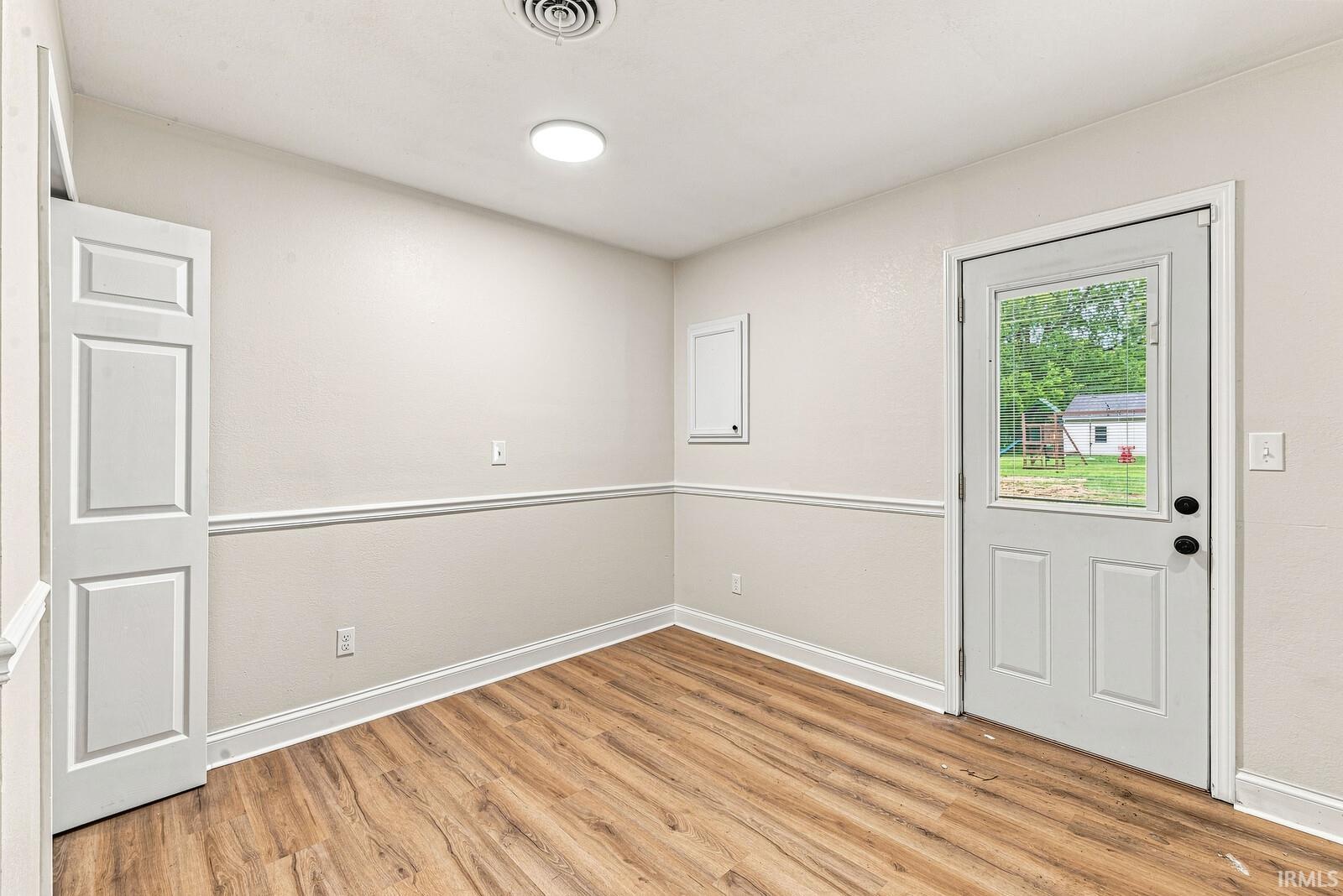 Wood-finish flooring, white paneled door, chair rail molding, and a back door with an inset window