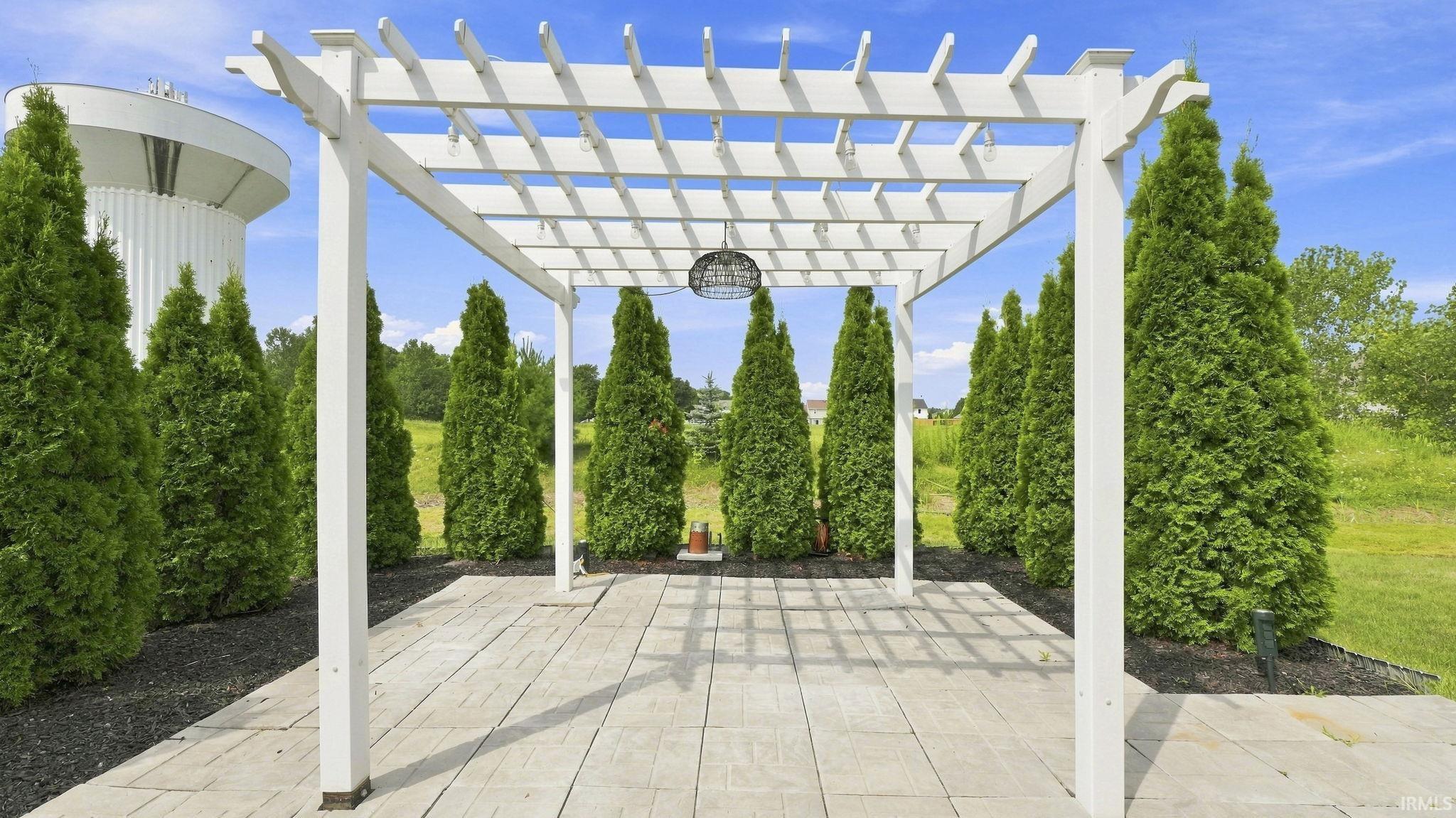 Elegant pergola with white aluminum frame and lattice roof design, anchoring a paver patio