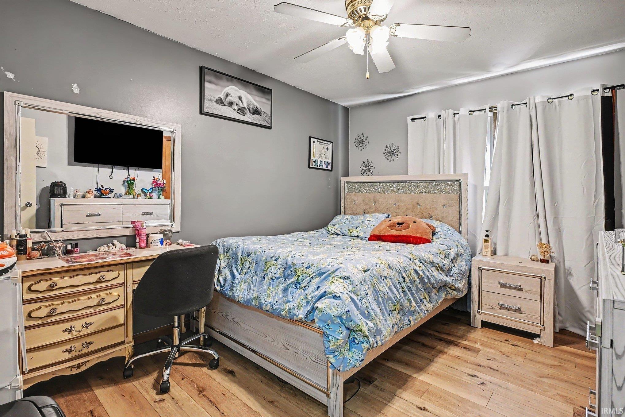 Hardwood-finish flooring, ceiling fan, and window with curtains