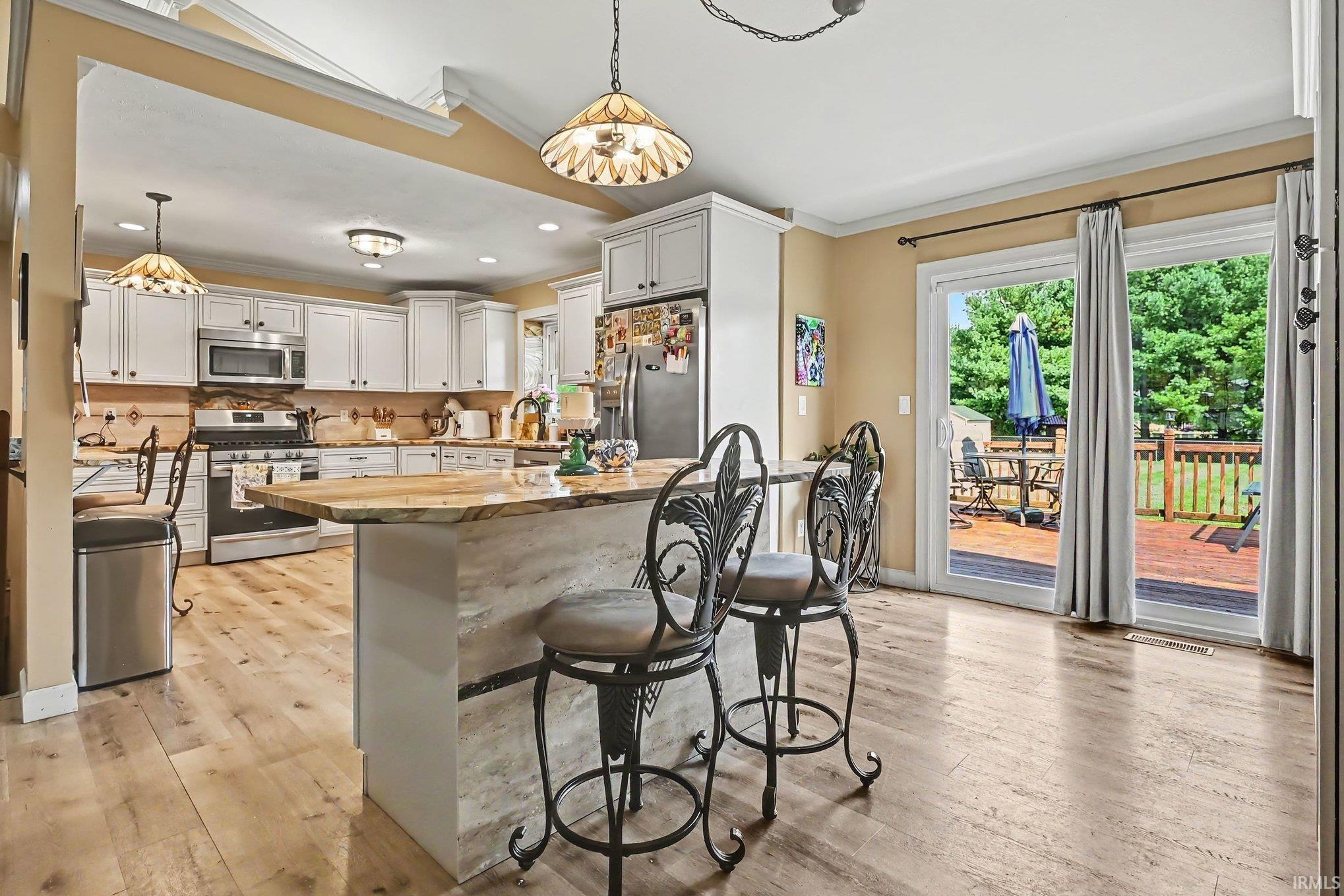 Spacious kitchen with white cabinetry, stainless steel appliances, a multi-level island, and wood-finish flooring