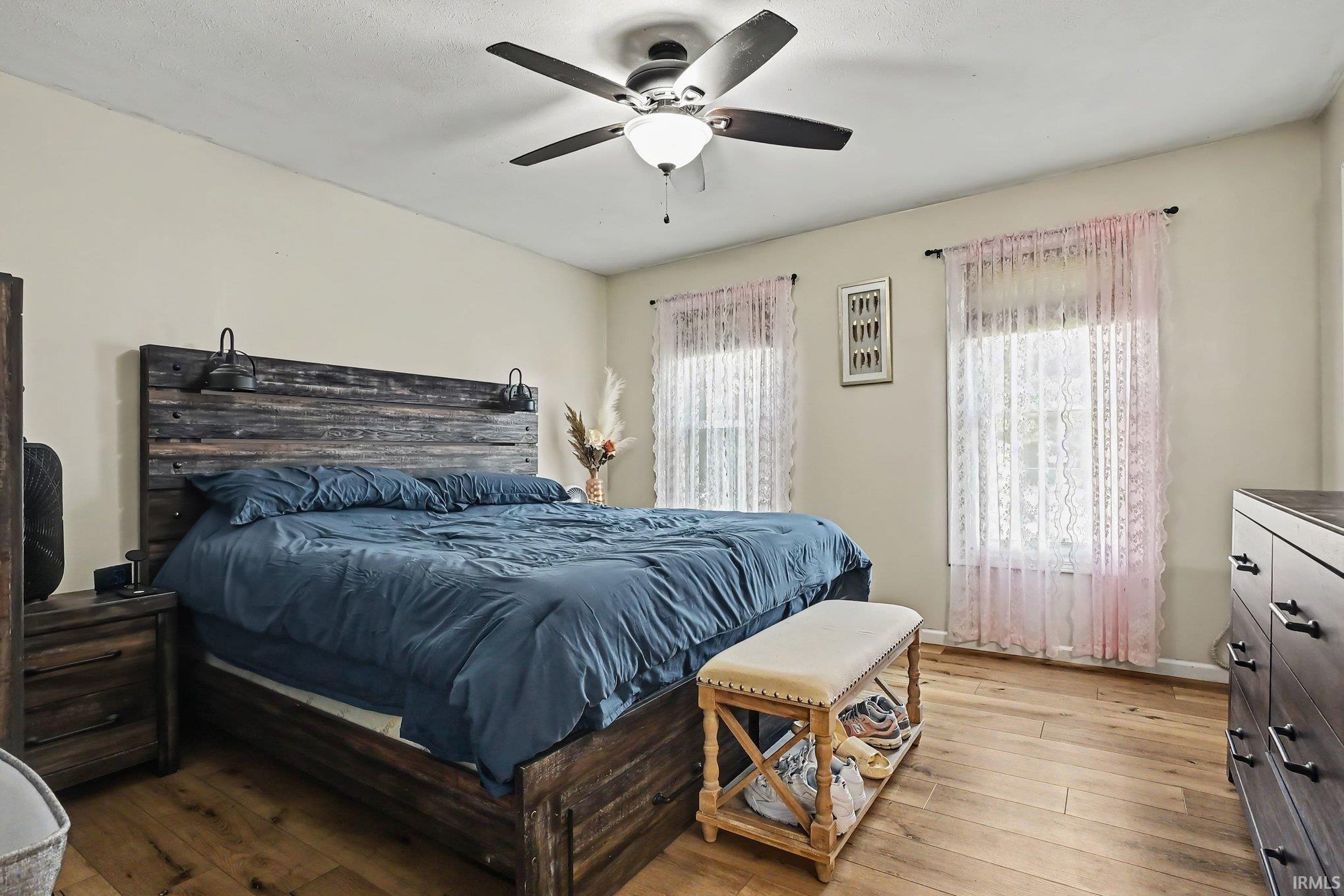 Wood-finish flooring with a ceiling fan and overhead lighting