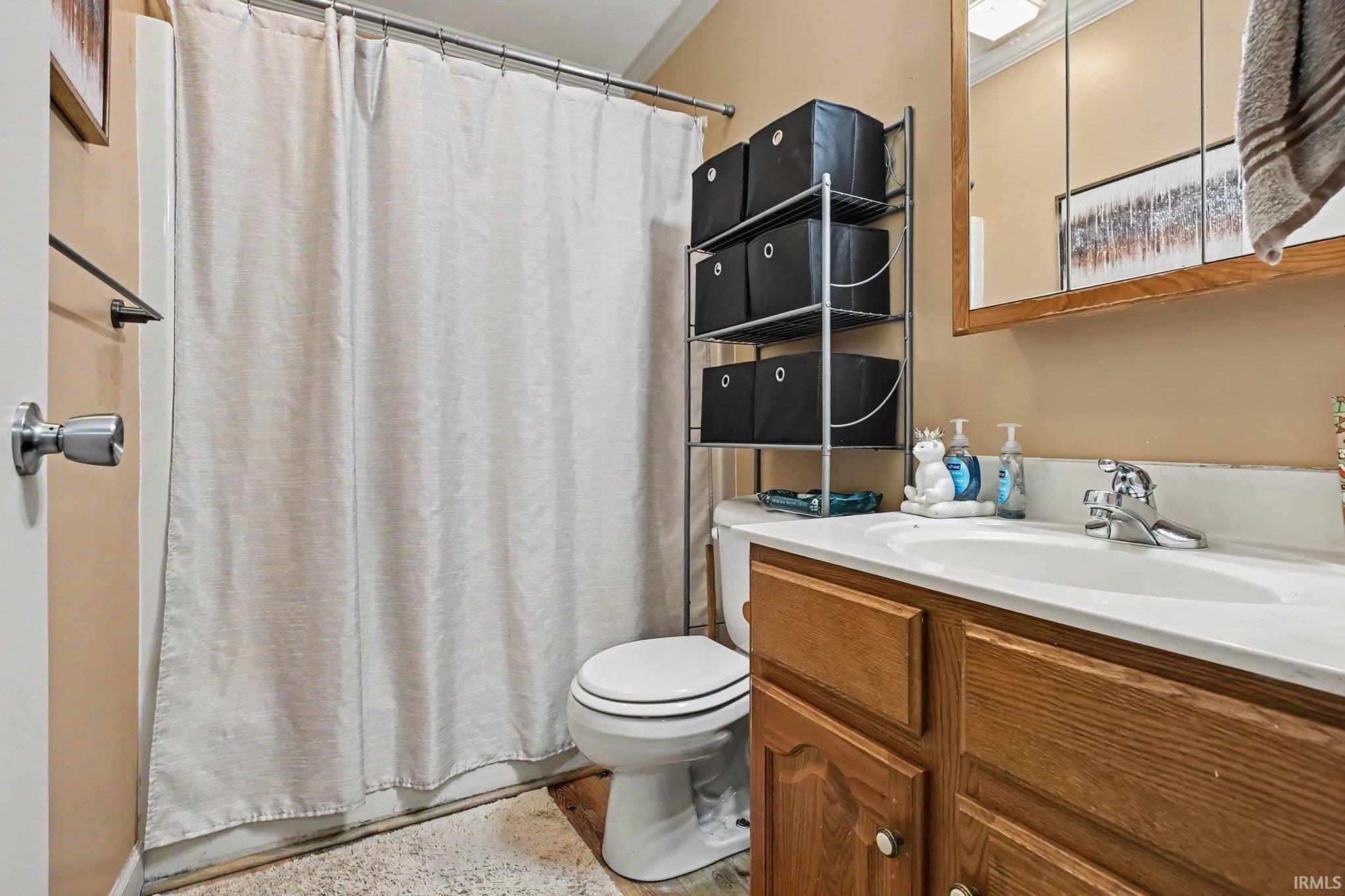 Vanity with wood-finish cabinetry, white countertop, and integrated sink