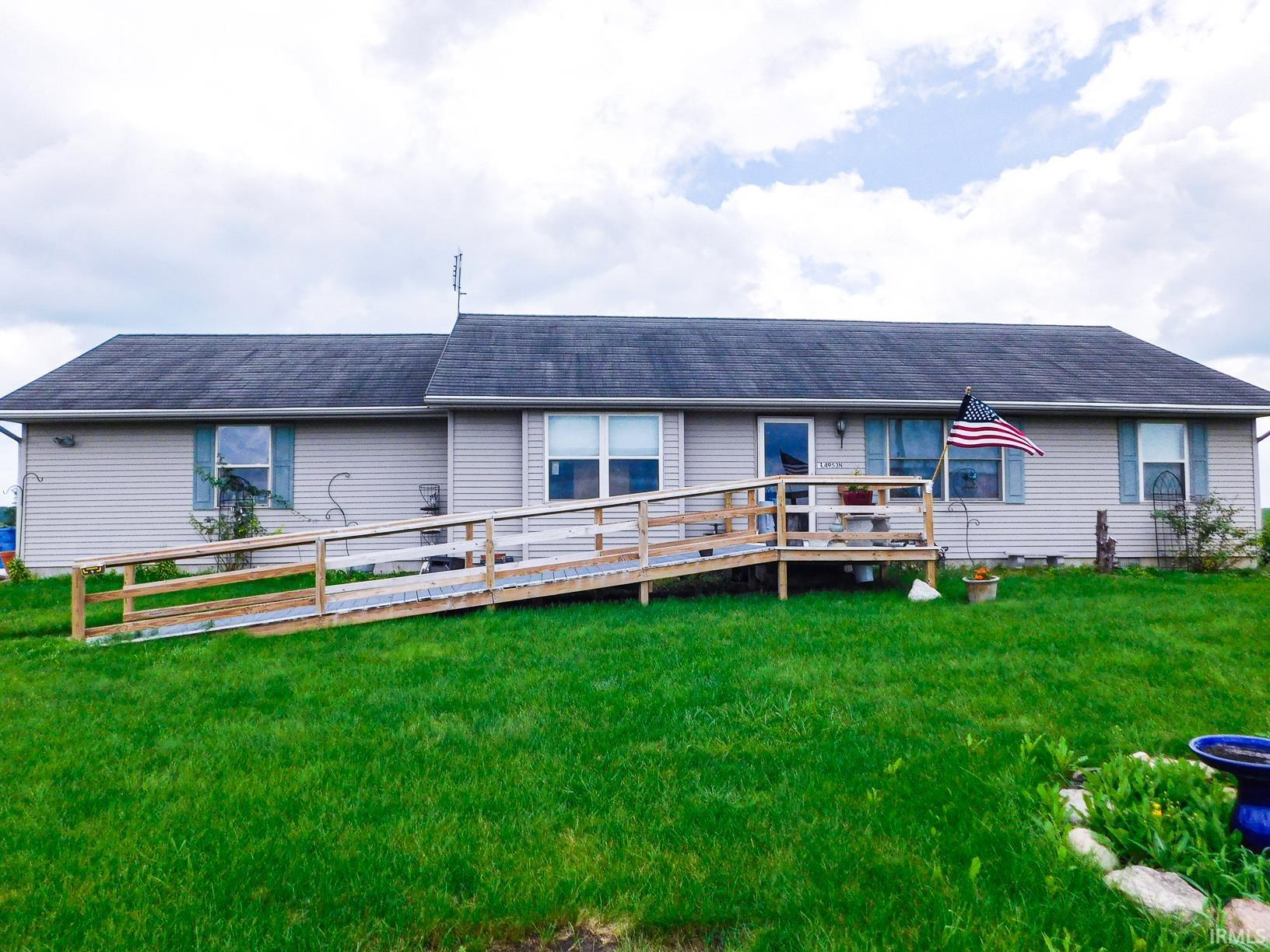 Light-colored horizontal siding, dark shingle roof, and a wood-framed access ramp