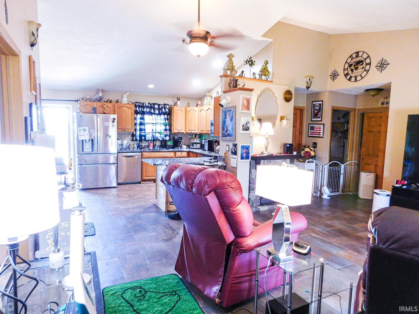 Spacious open-concept living area with vaulted ceilings, recessed lighting, wood-finish flooring, and a kitchen featuring stainless steel appliances and wood cabinetry