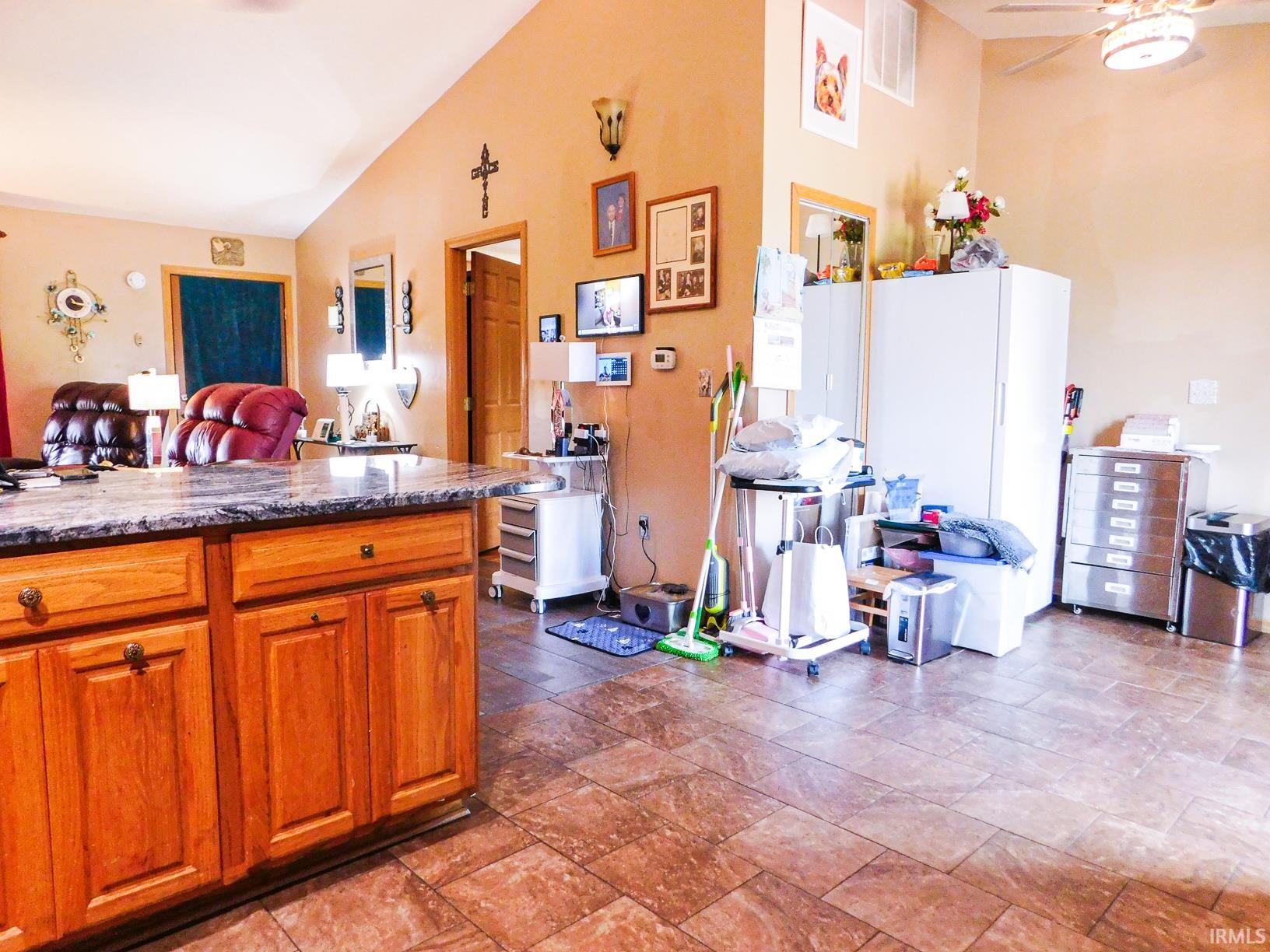 Wood-finish flooring throughout, vaulted ceiling, wood cabinetry, and a ceiling fan with integrated lighting