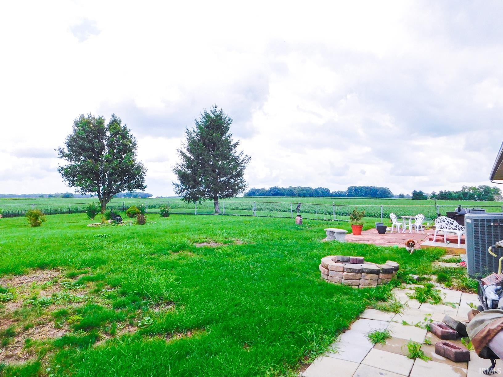 Expansive lawn with mature trees and a brick paver patio