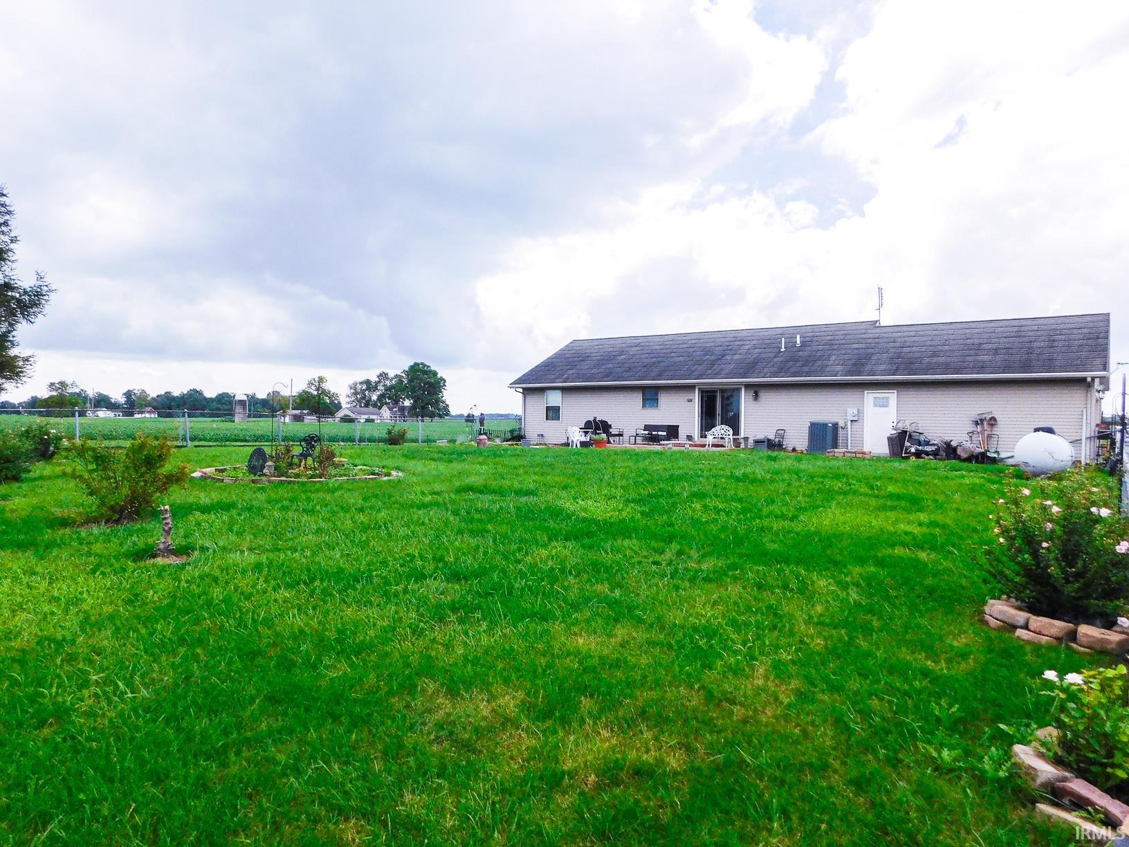 Expansive rural property featuring substantial acreage with lush green pastureland, a single-story residential structure with light-colored exterior siding, and open grounds ideal for agricultural or recreational pursuits