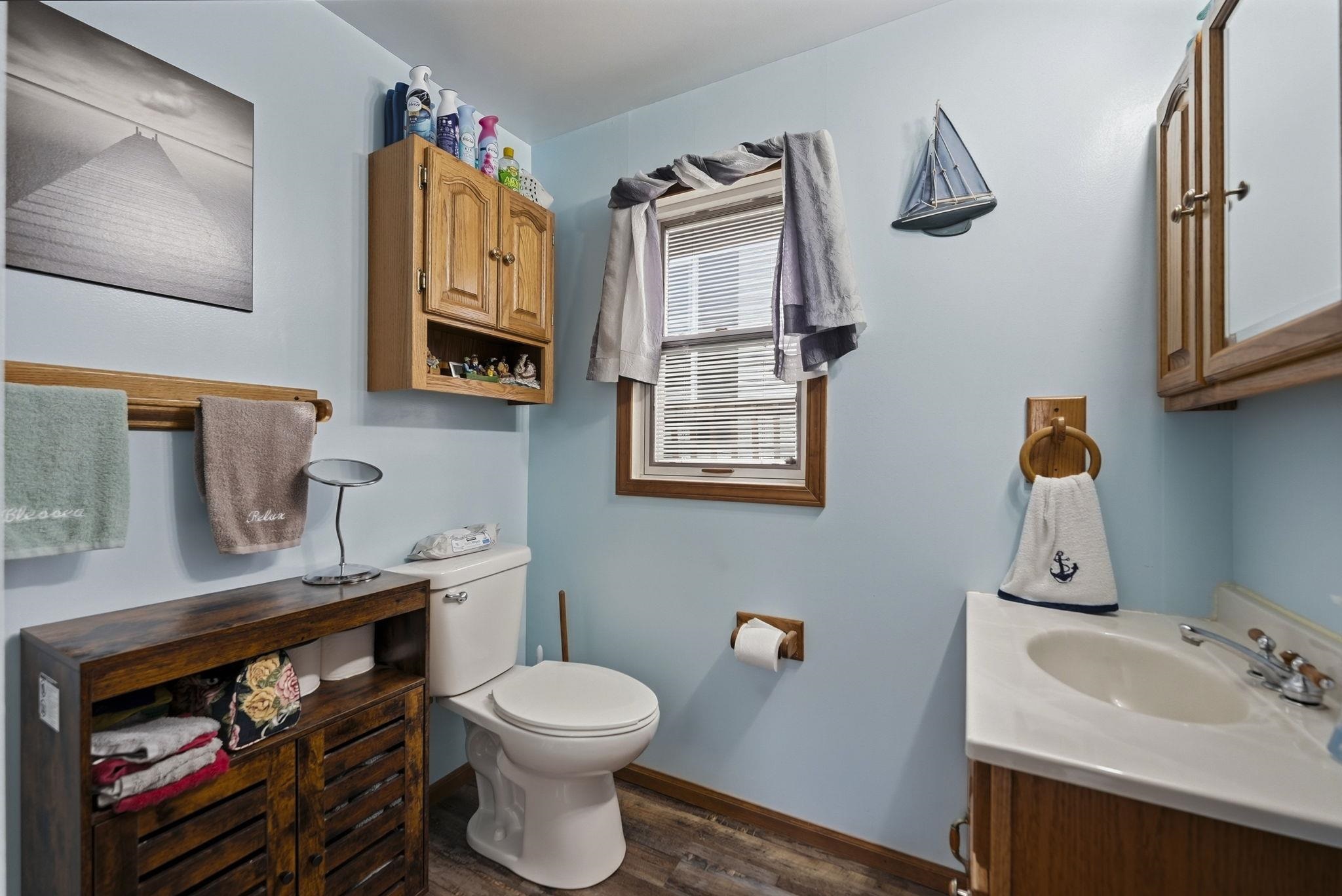 Wood-finish flooring, wood cabinetry, and a white sink with a laminate countertop