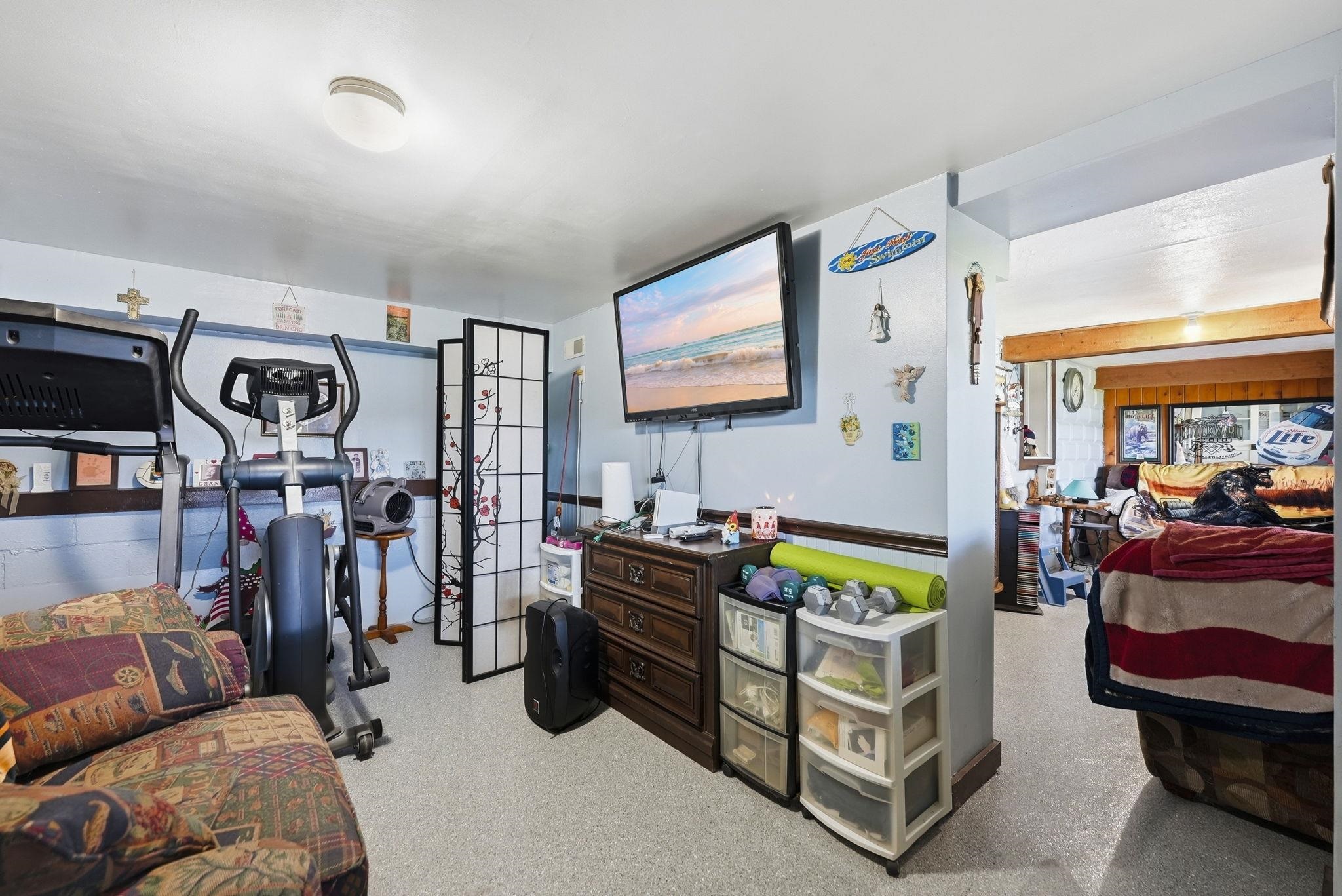 Light-colored flooring, wall-mounted television, and a wooden chest of drawers