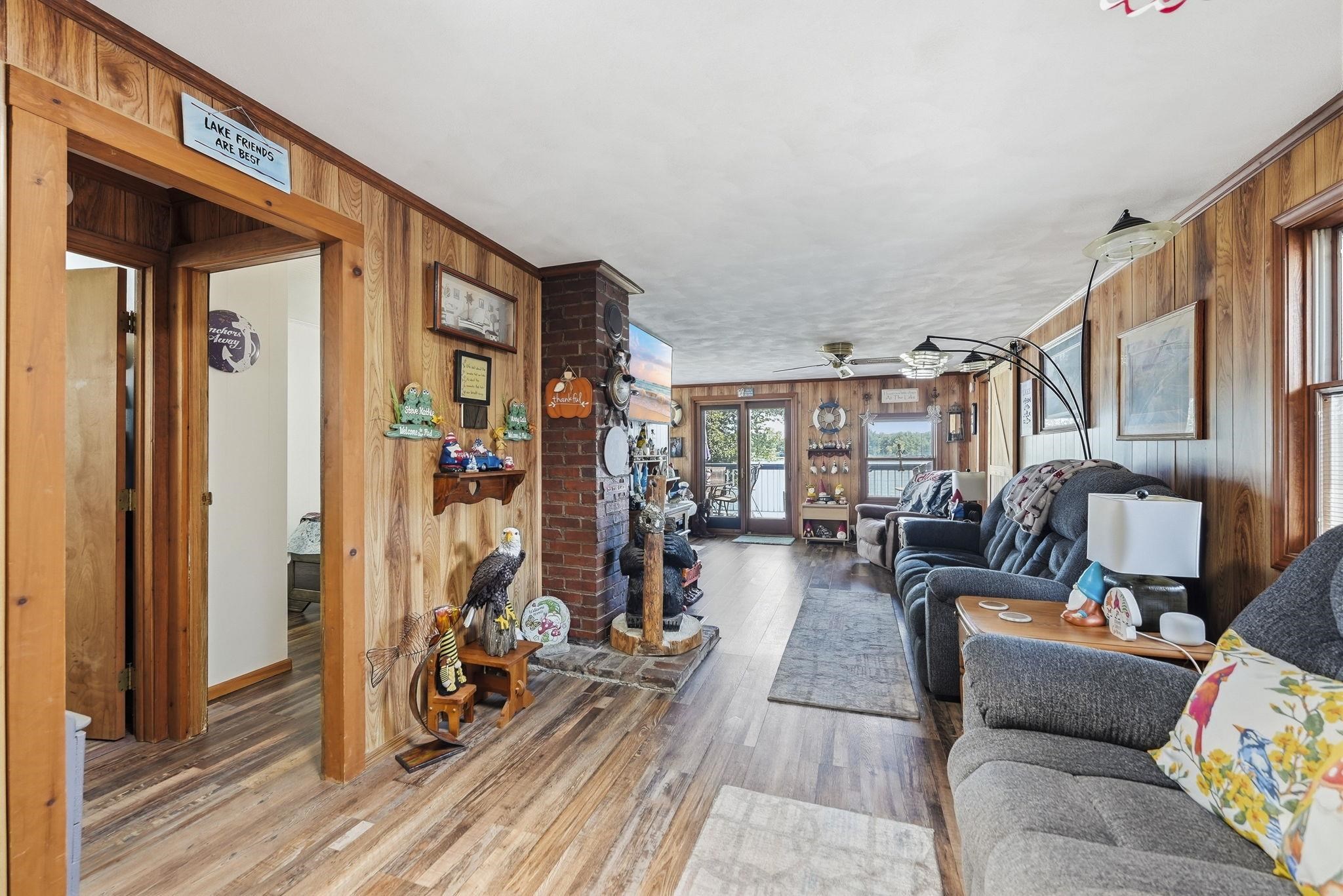 Wood-finish flooring throughout, wood-paneled walls, and a brick fireplace