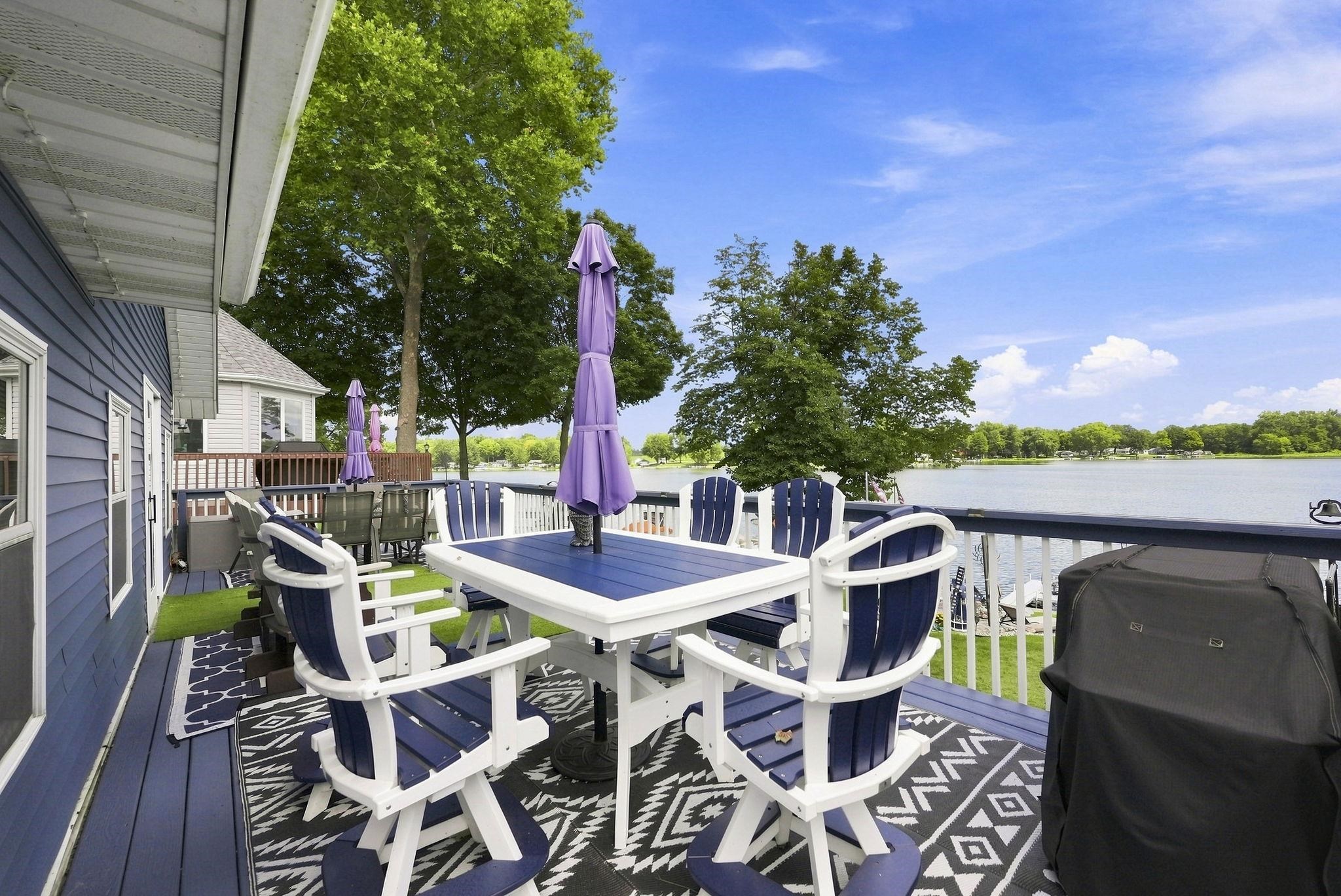 Expansive outdoor deck with a dark blue finish, white railings, and direct water frontage