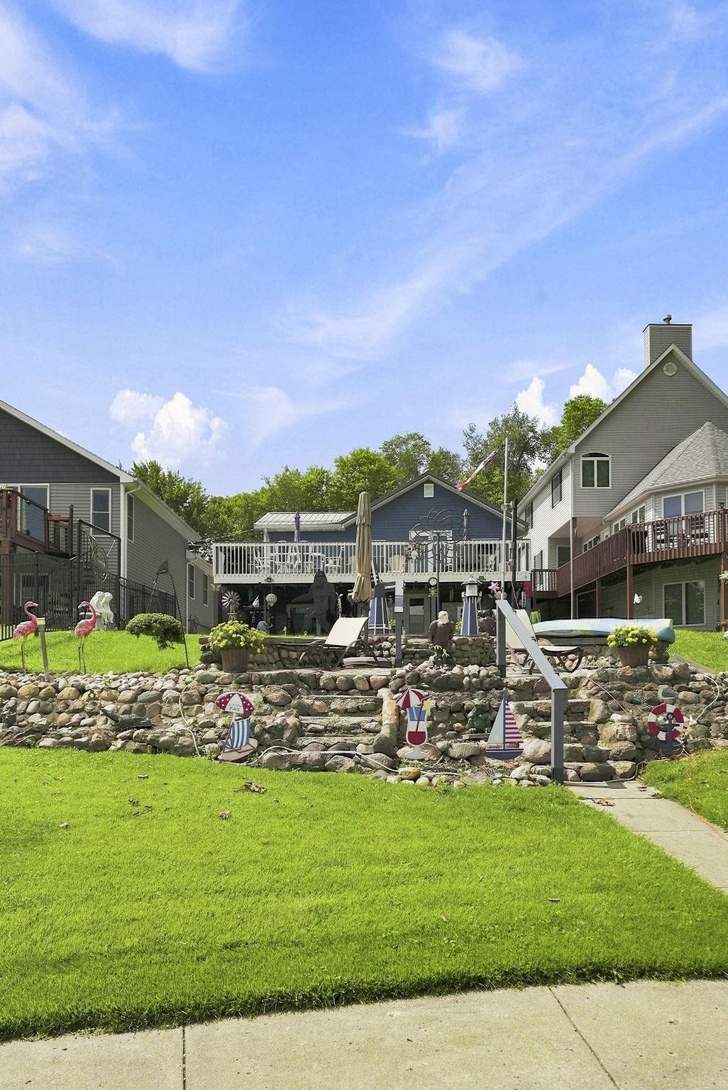 Two-story residence featuring an upper-level deck, a lower patio, and a stone-clad terraced landscape
