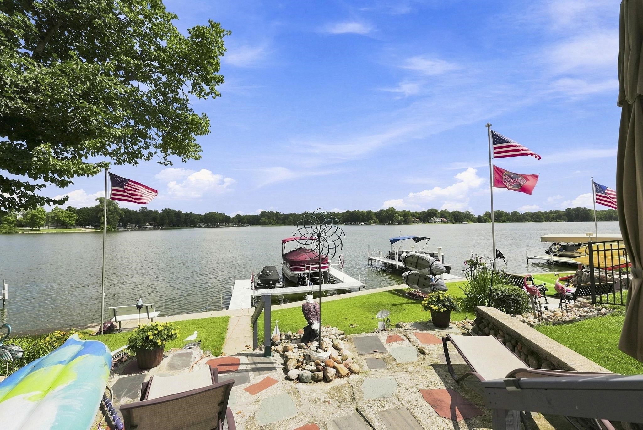 Waterfront property with a stone patio, manicured lawn, and private boat dock
