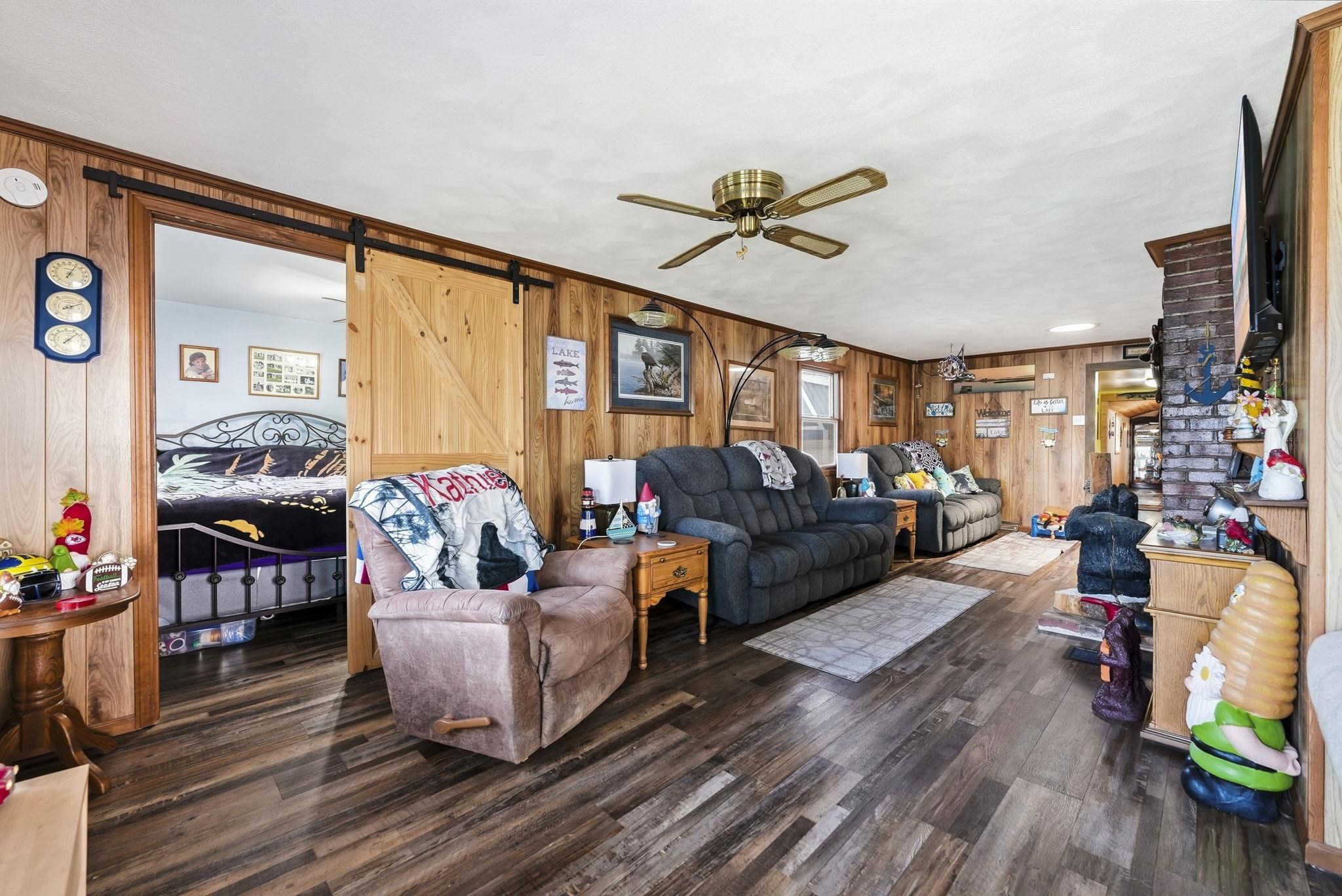 Wood-finish flooring throughout, wood-paneled walls, and a ceiling fan with integrated lighting