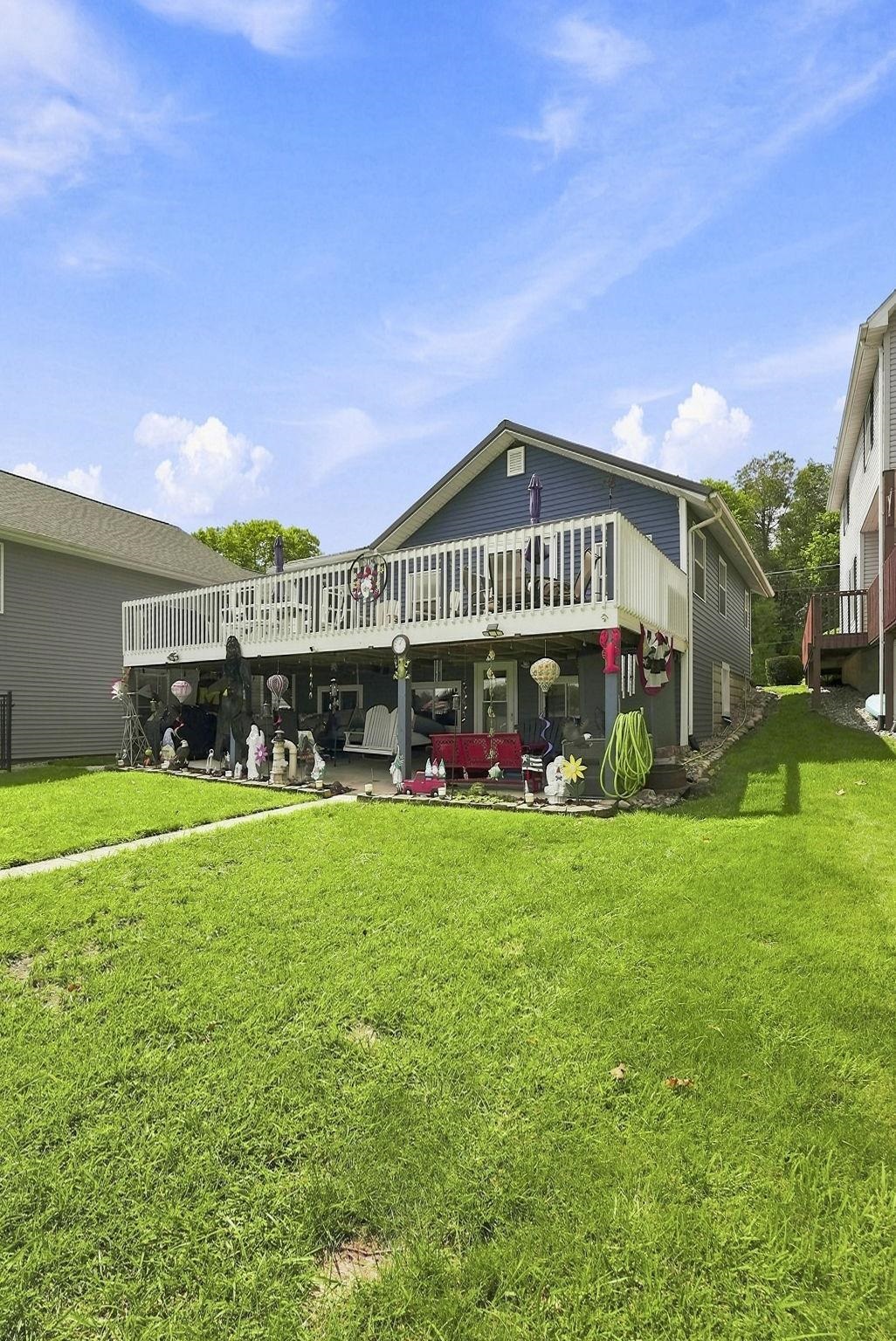 Expansive green lawn with a two-story exterior featuring a full-width upper deck and a covered lower patio