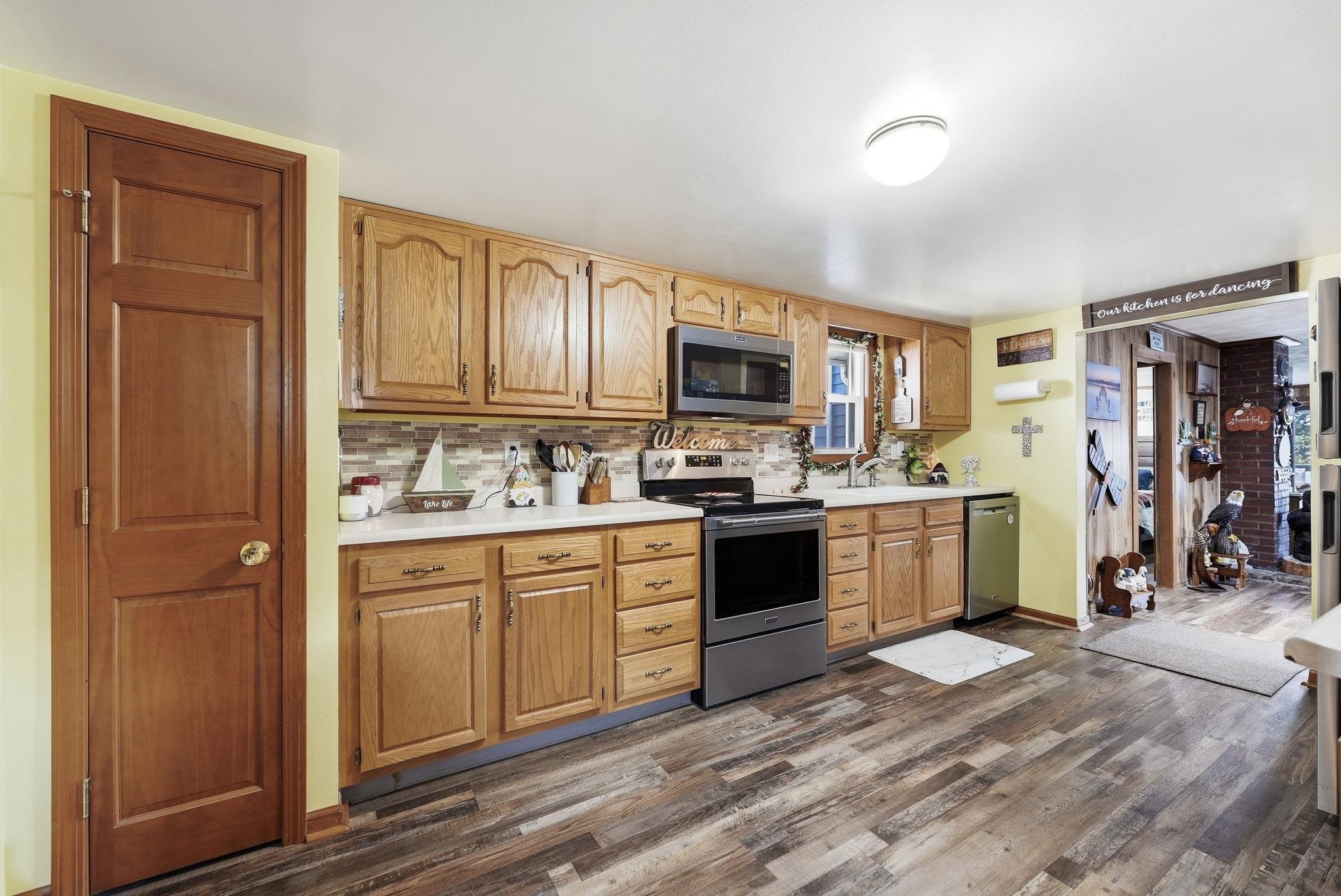 Kitchen featuring wood-finish flooring, oak cabinetry, white countertops, and stainless steel appliances