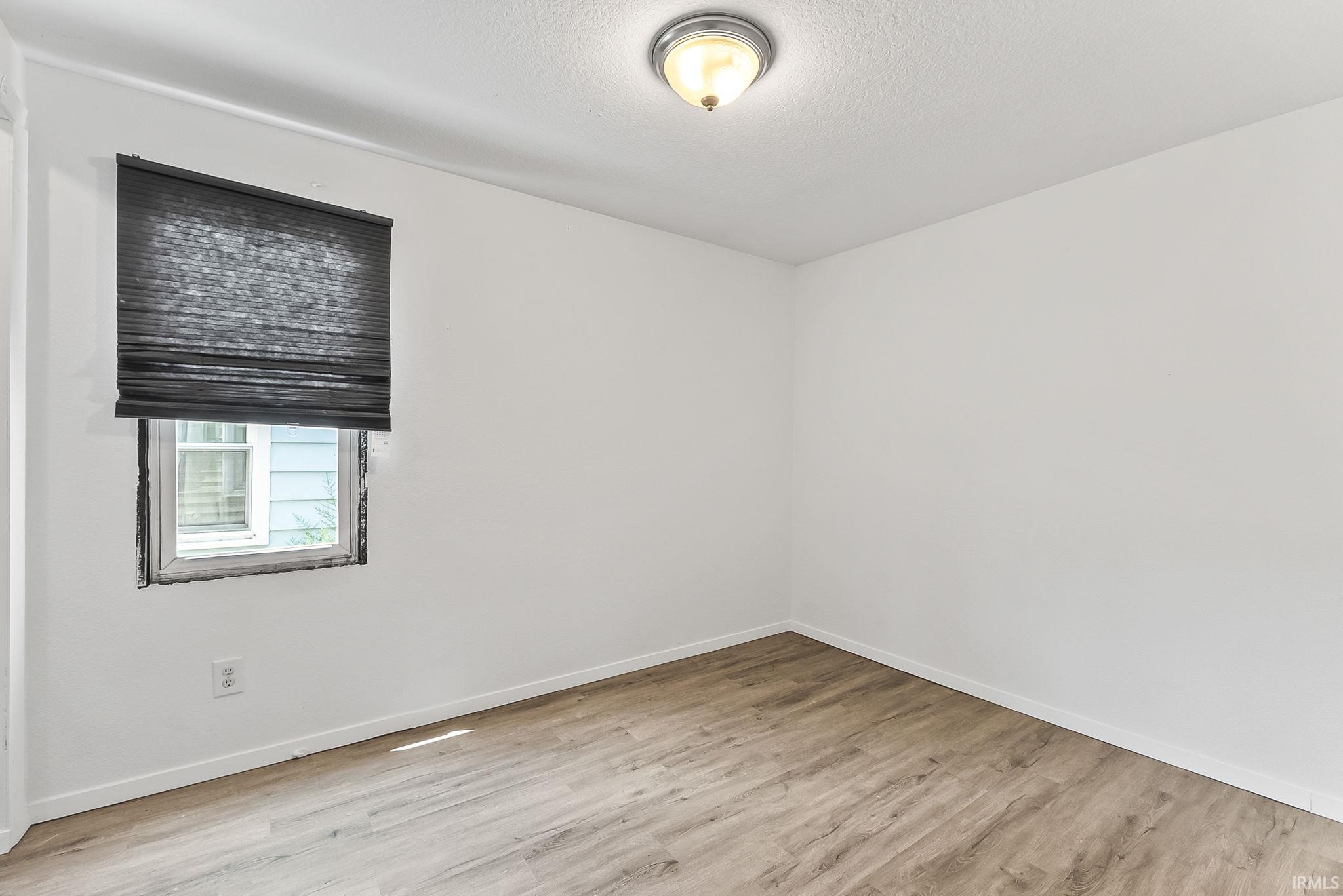 Wood-finish flooring with white baseboards and light-toned walls