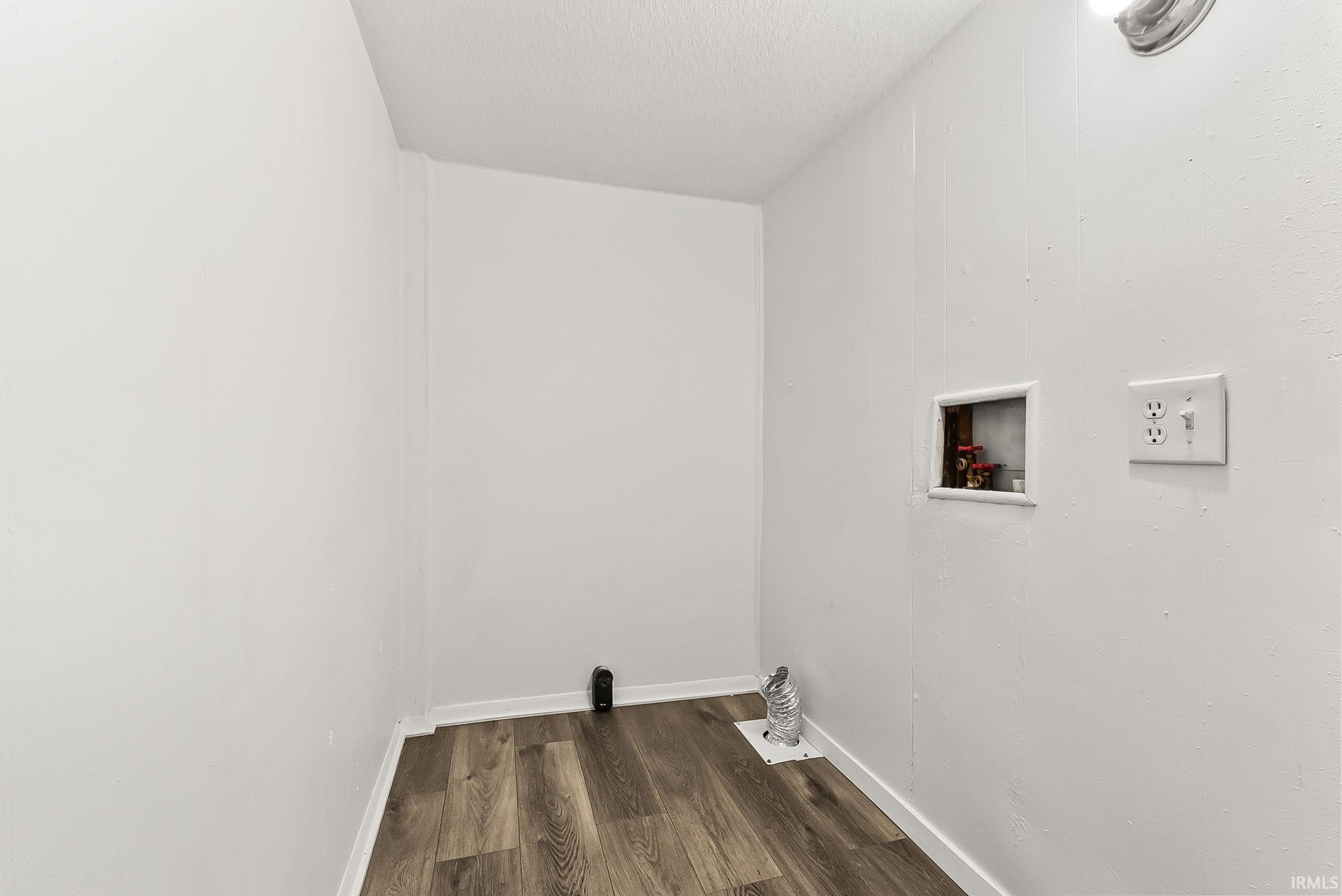 Wood-finish flooring with white baseboards, and a dedicated laundry area with utility hookups and electrical outlets