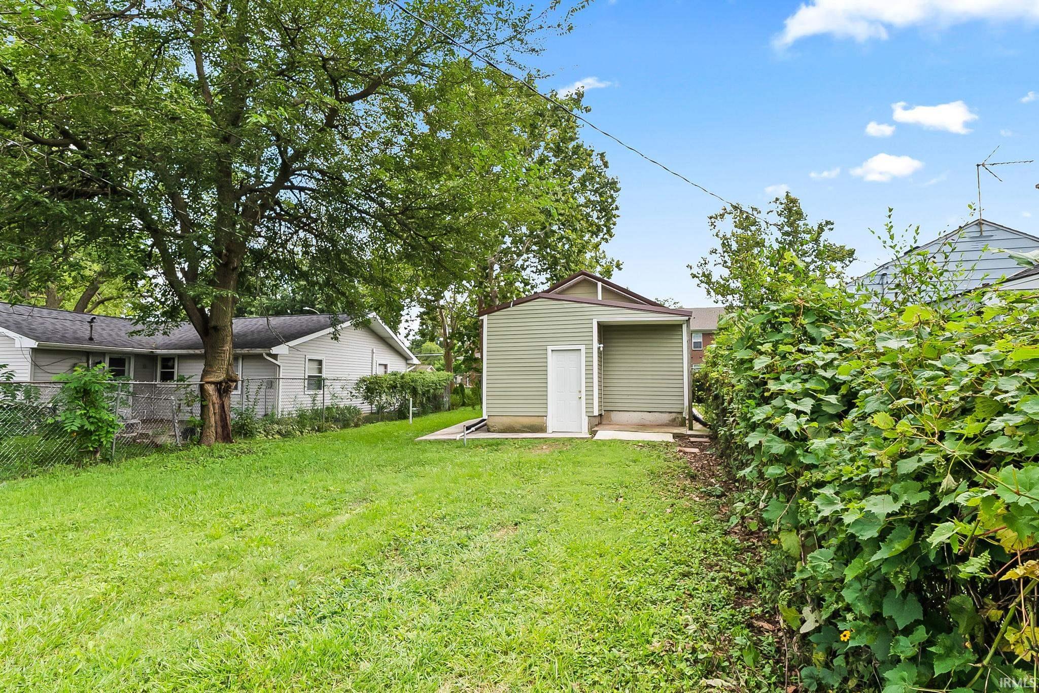 Detached shed with siding, concrete pad, and a white entry door