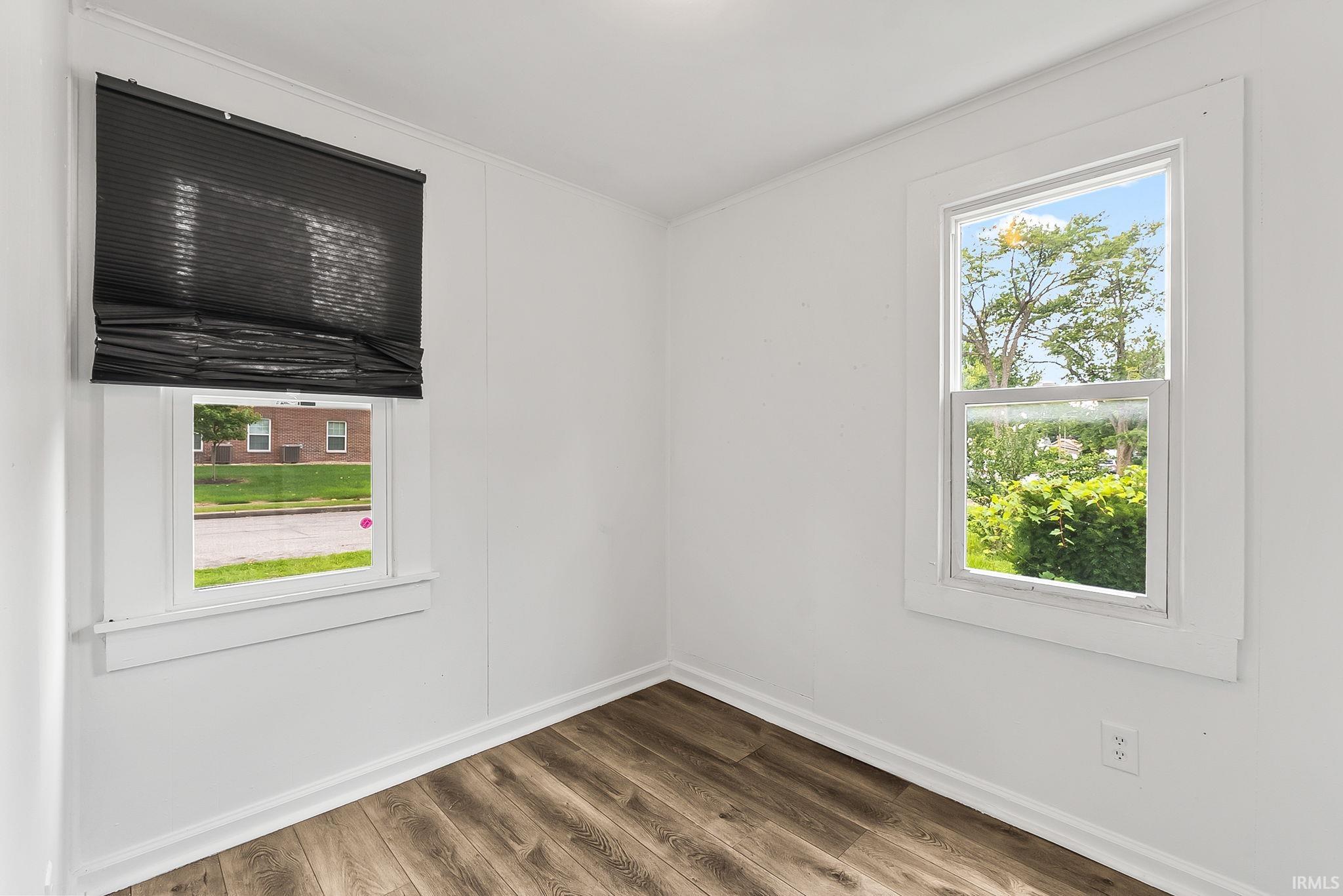 Wood-finish flooring, white walls, and two windows with white trim