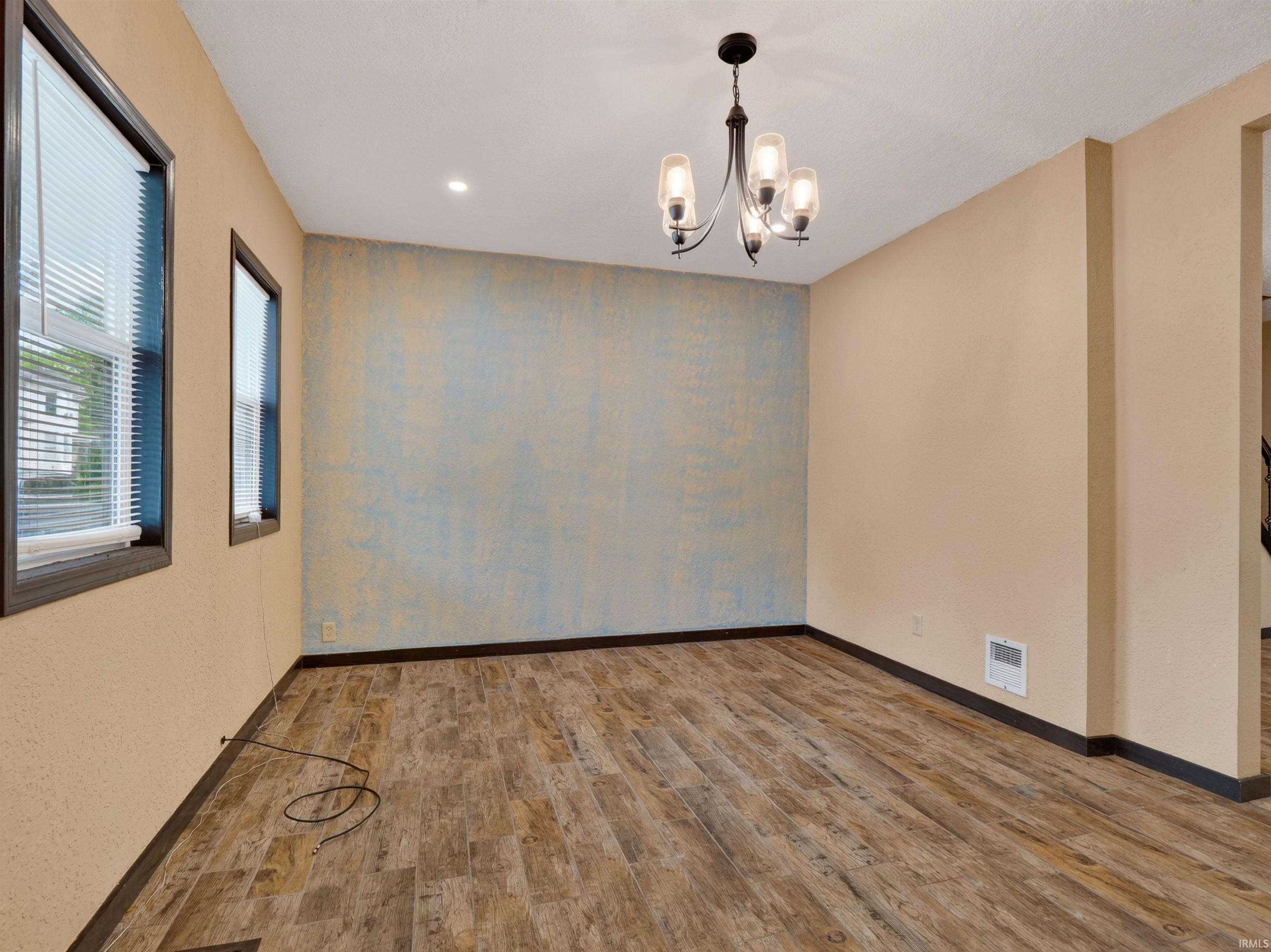 Wood-finish flooring, recessed ceiling lighting, and a chandelier with glass shades