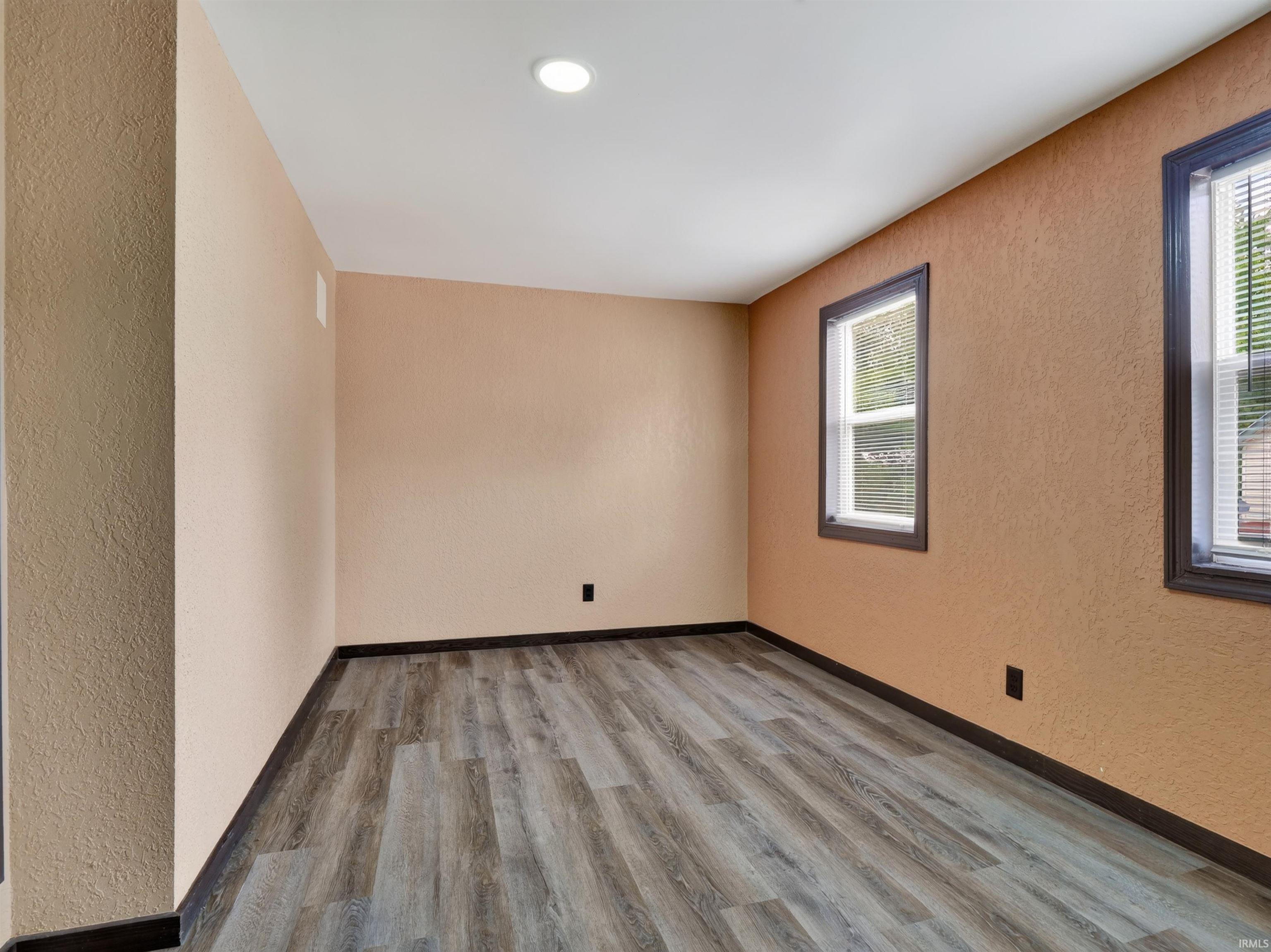 Recessed ceiling lighting, two windows with blinds, and wood-finish plank flooring