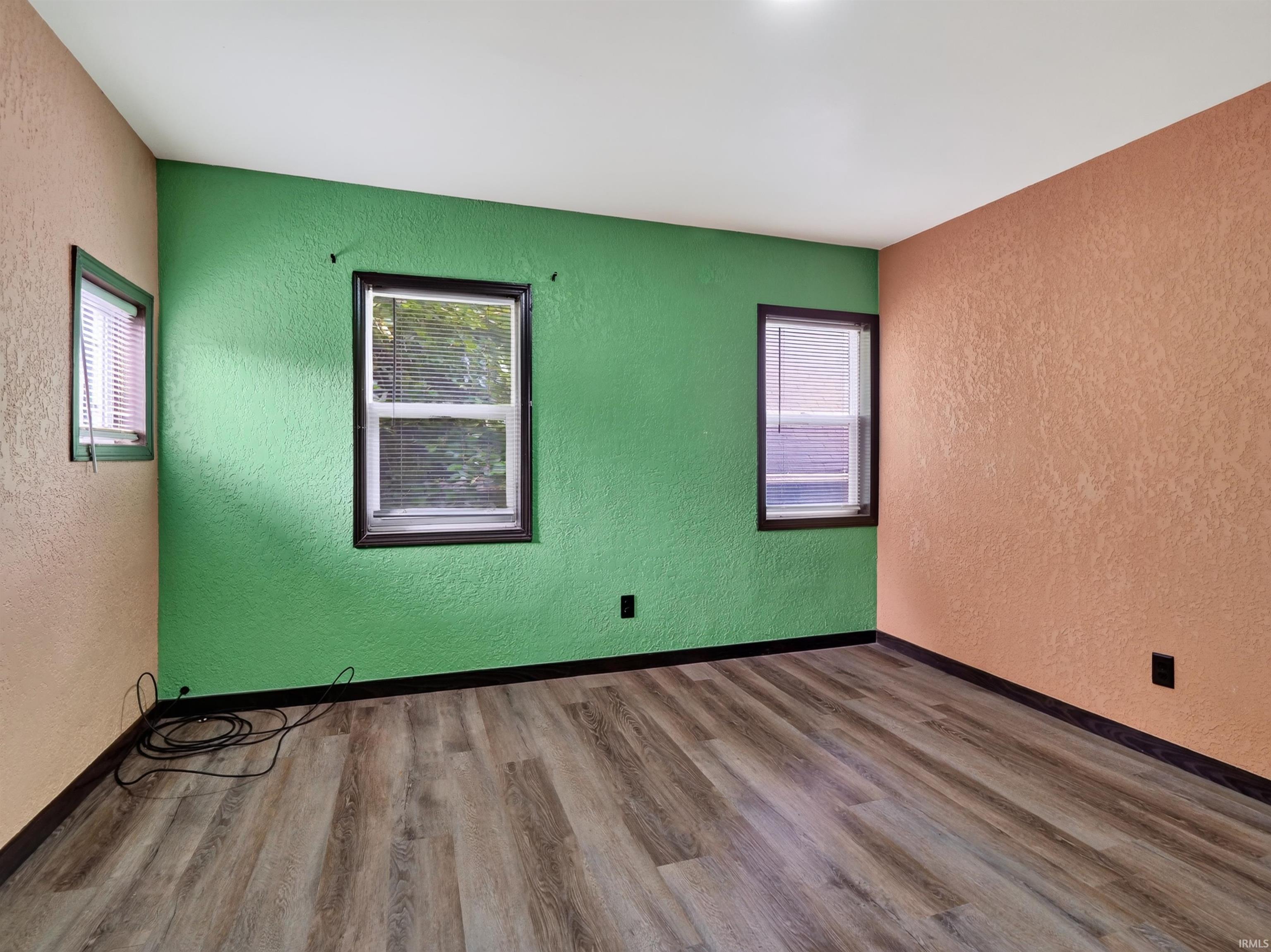 Wood-finish flooring with black trim, three windows, and overhead lighting