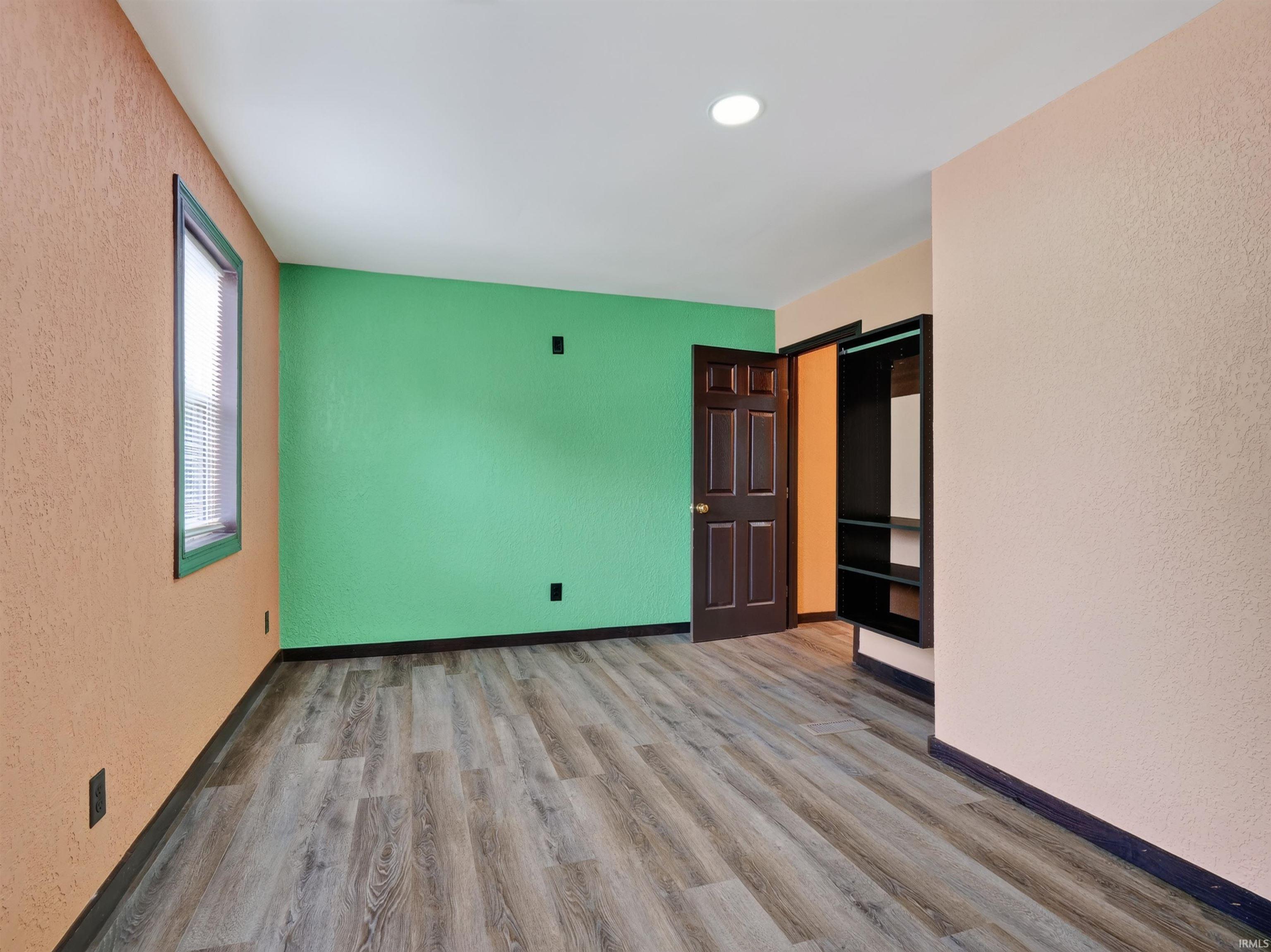 Wood-finish flooring, recessed ceiling light, paneled door, and built-in closet shelving