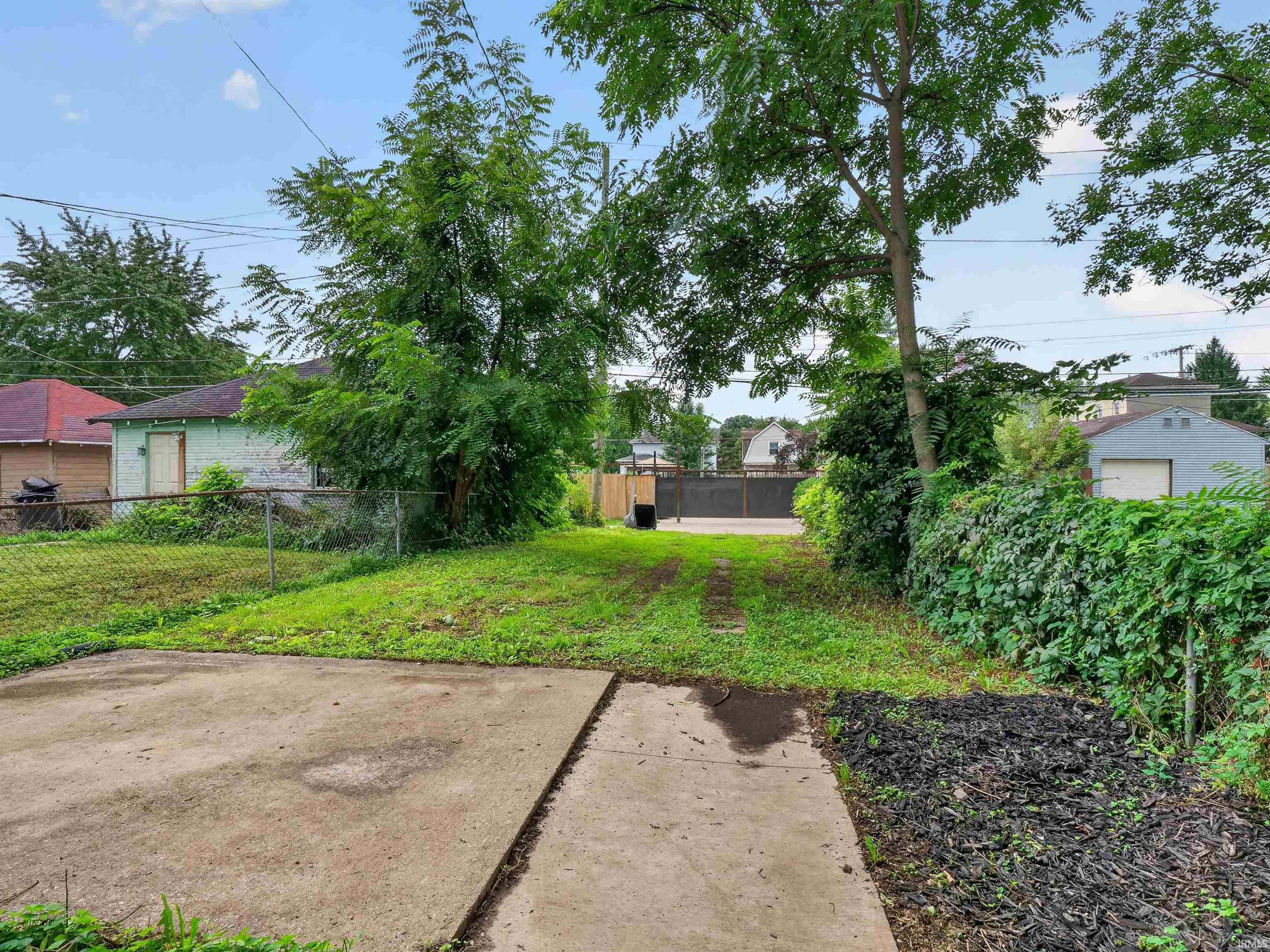 Expansive green space featuring established trees and a concrete patio