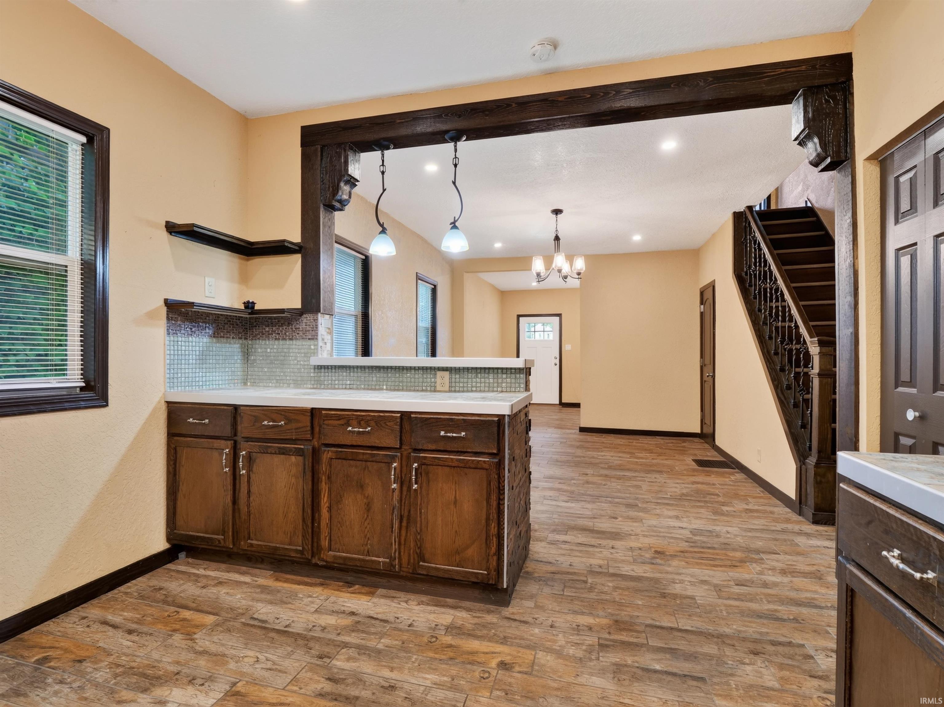 Wood-finish flooring throughout, featuring a kitchen peninsula with wood cabinetry and a tile backsplash