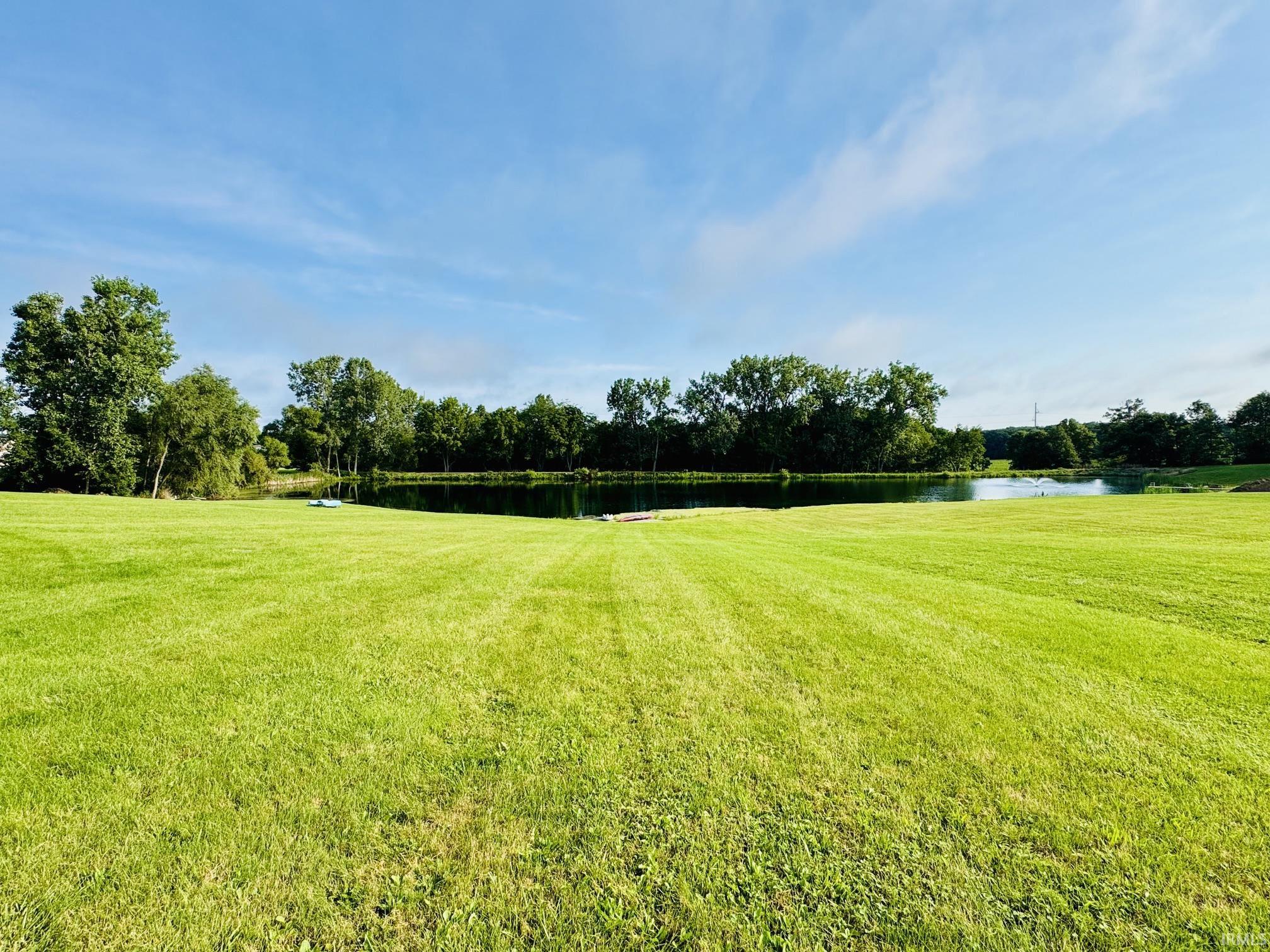 Expansive green lawn with a water feature bordered by mature trees