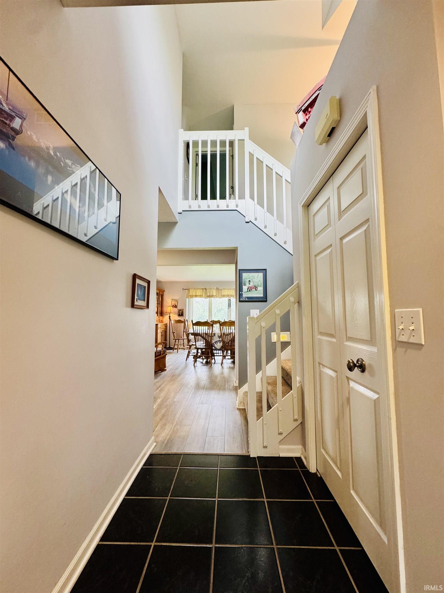 Foyer with black tile flooring, high ceilings, and a white balustrade staircase