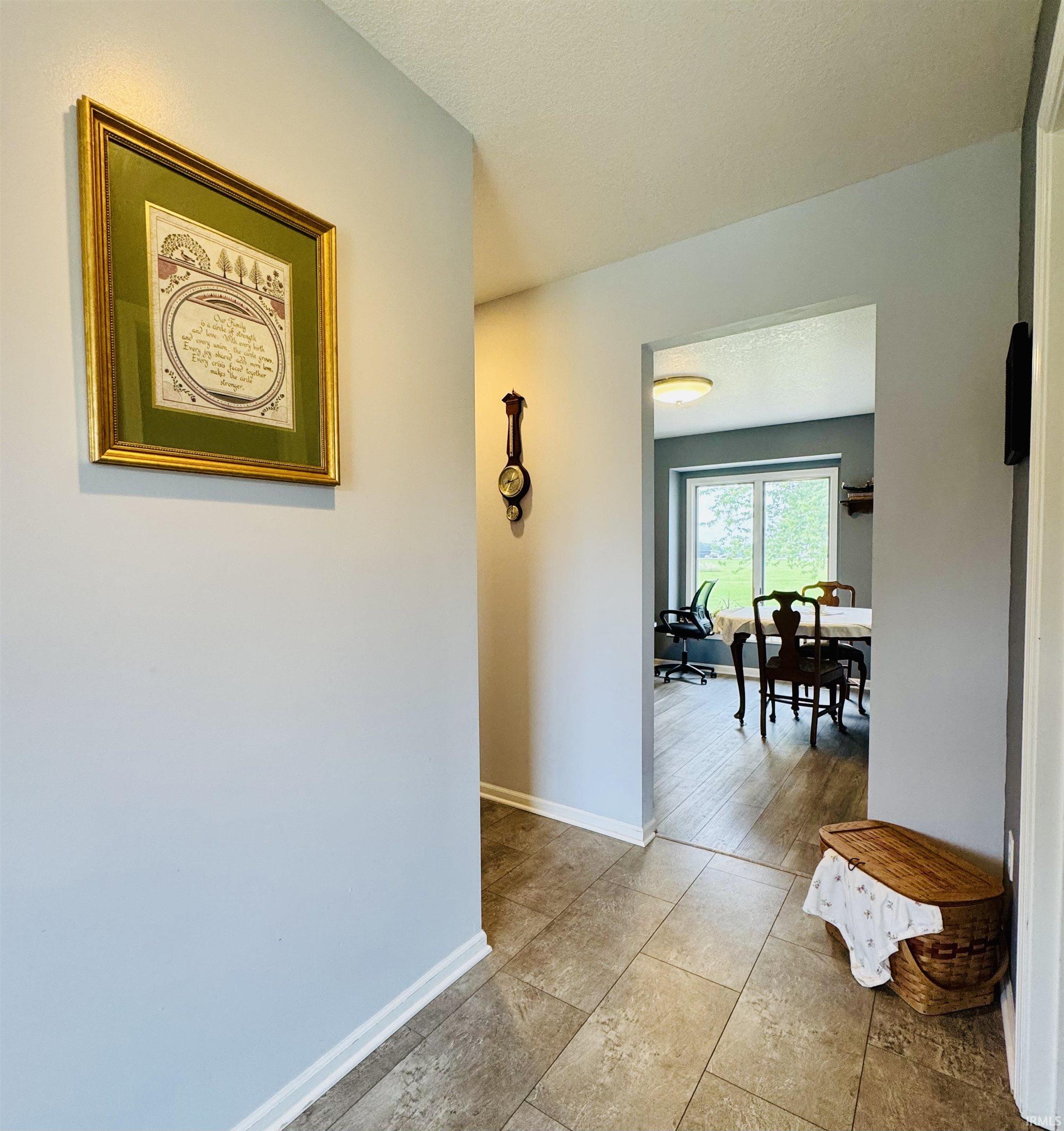 Tile flooring in the entryway, leading to an open doorway with wood-finish flooring in the adjacent room