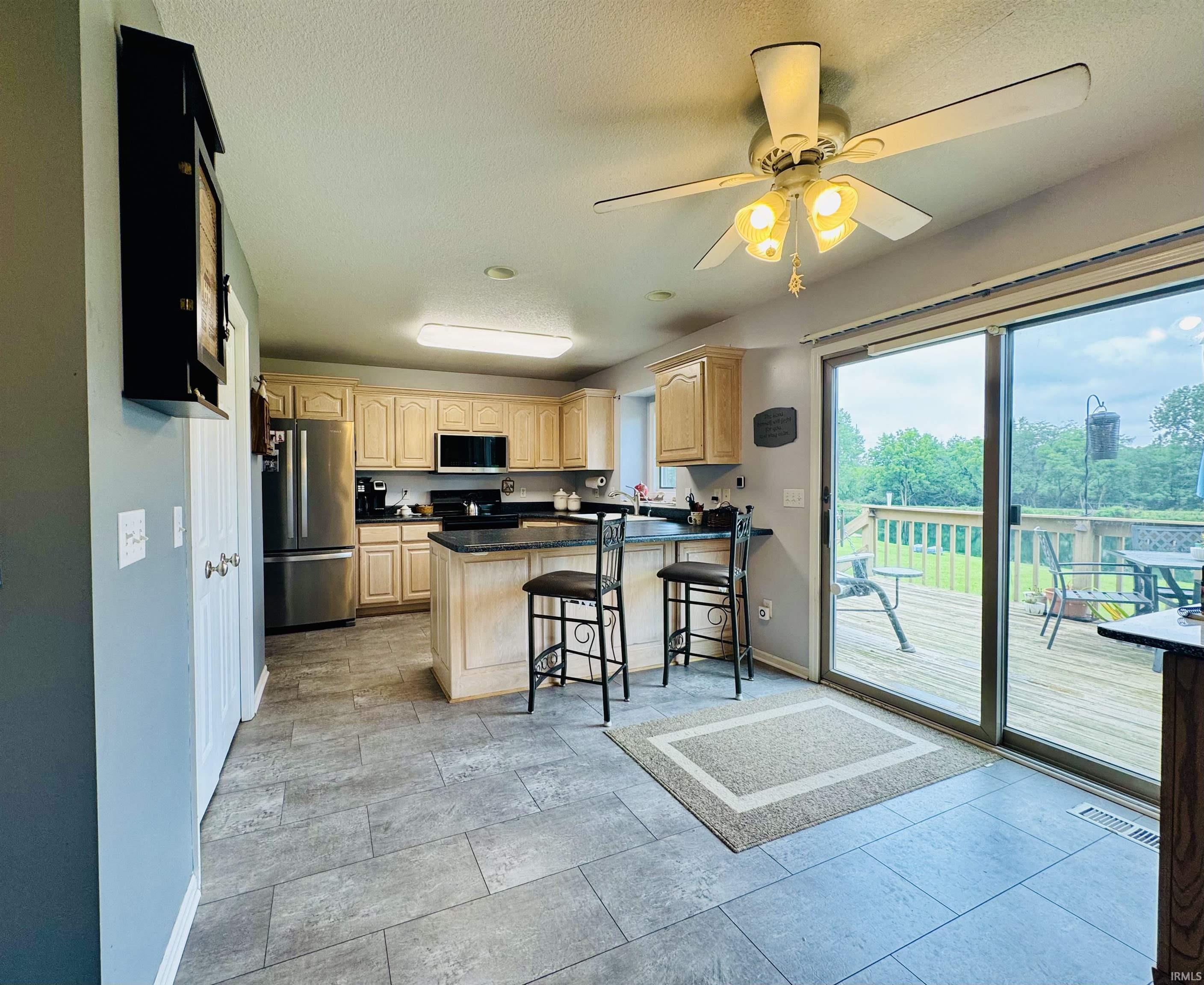 Kitchen featuring stainless steel appliances, light-toned cabinetry, and dark countertops