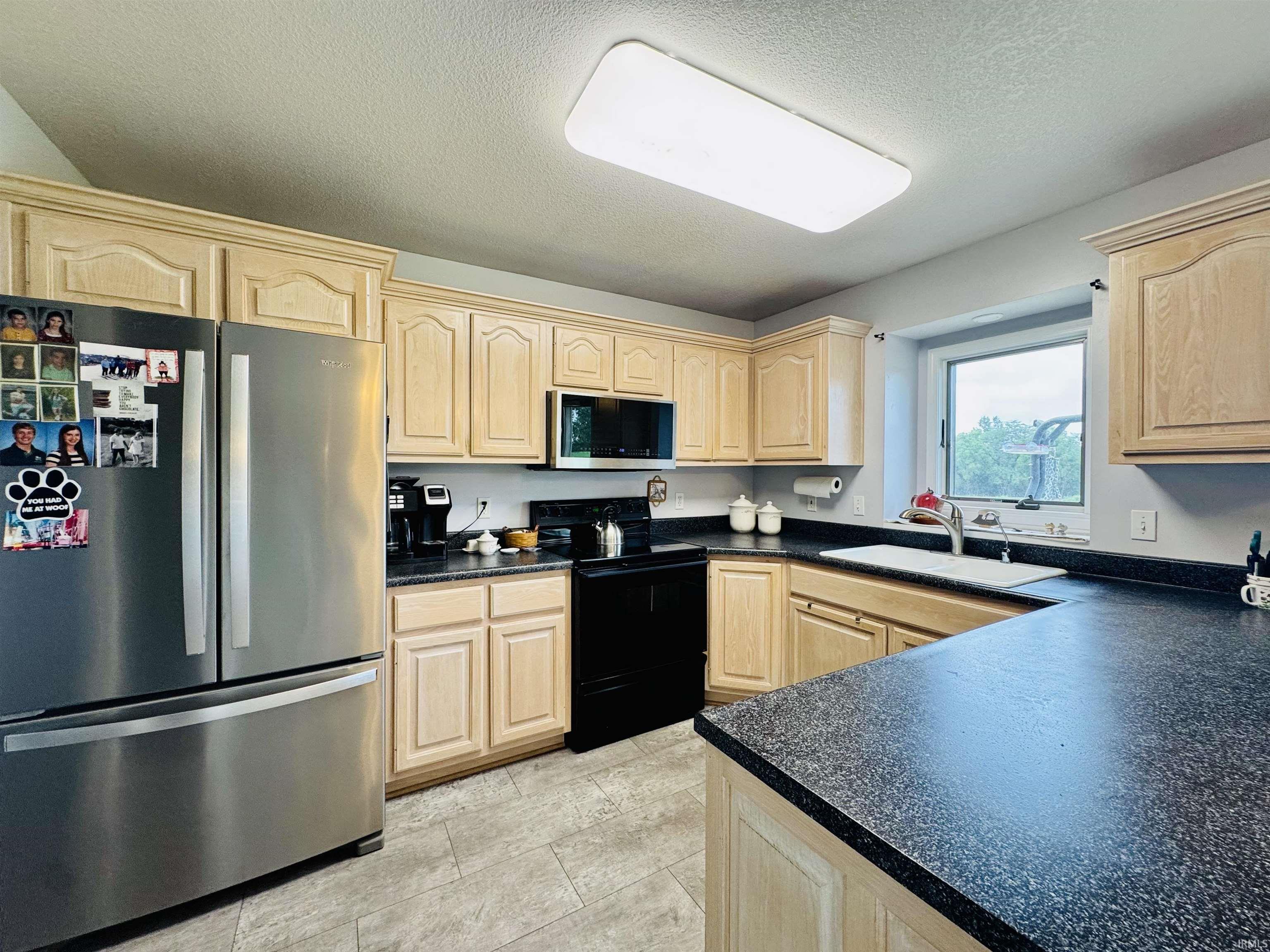 Kitchen featuring wood cabinetry, dark countertops, and stainless steel appliances
