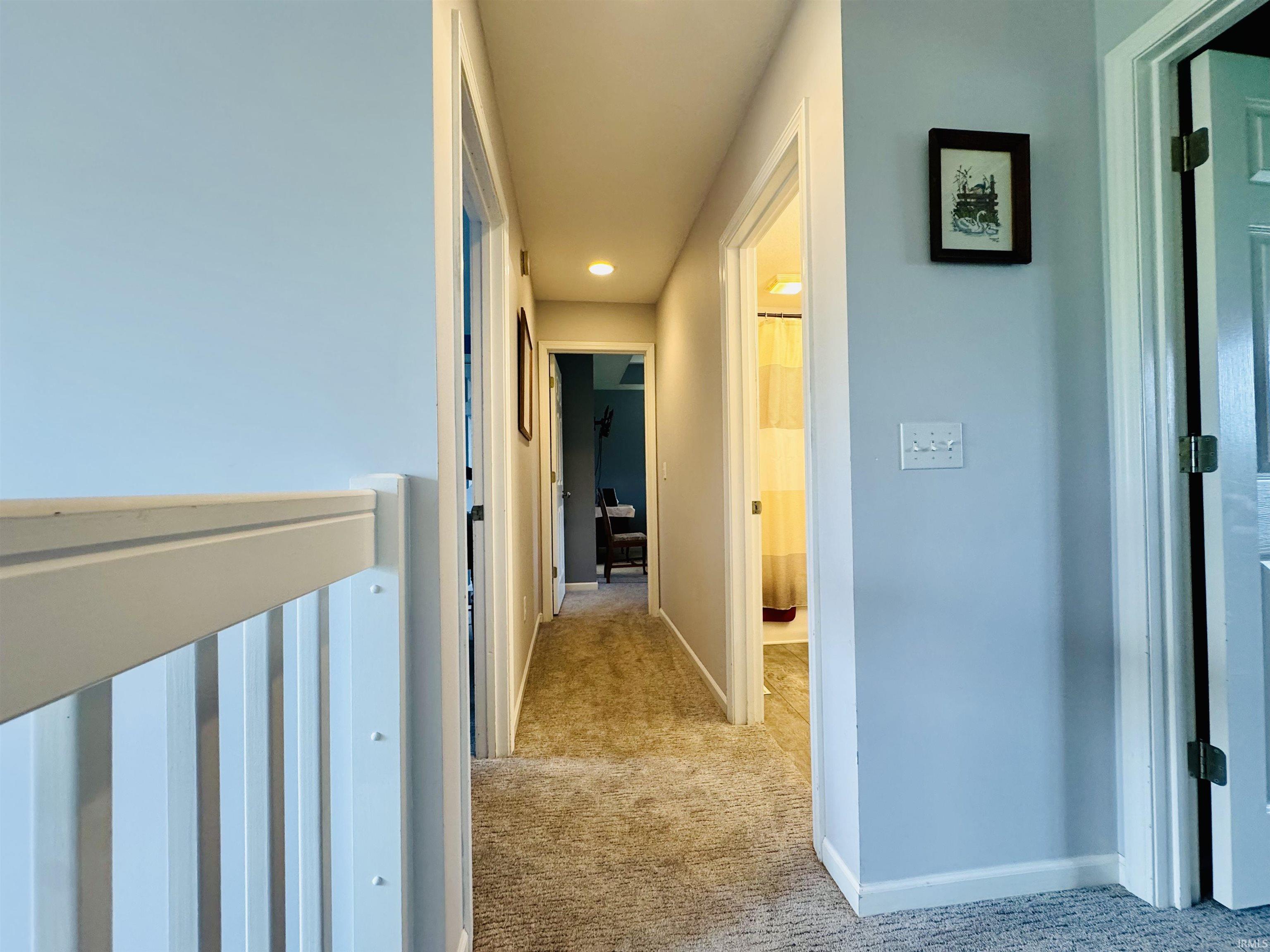 Carpeted hallway with light blue walls and white trim