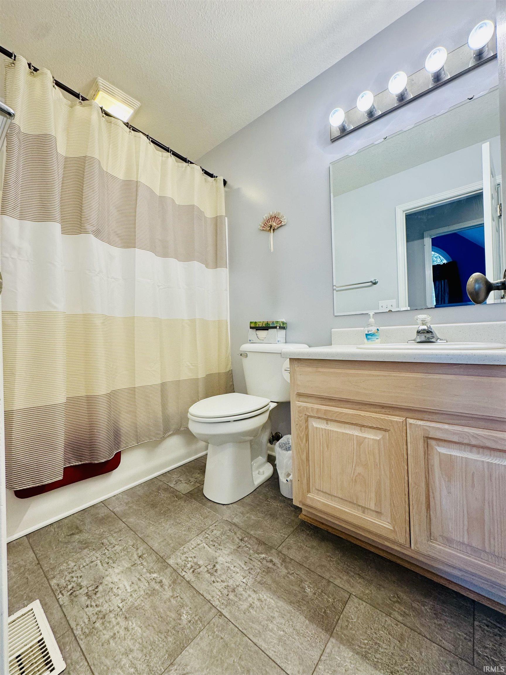 Bathroom featuring wood-finish flooring, a vanity with a laminate countertop, and a built-in toilet