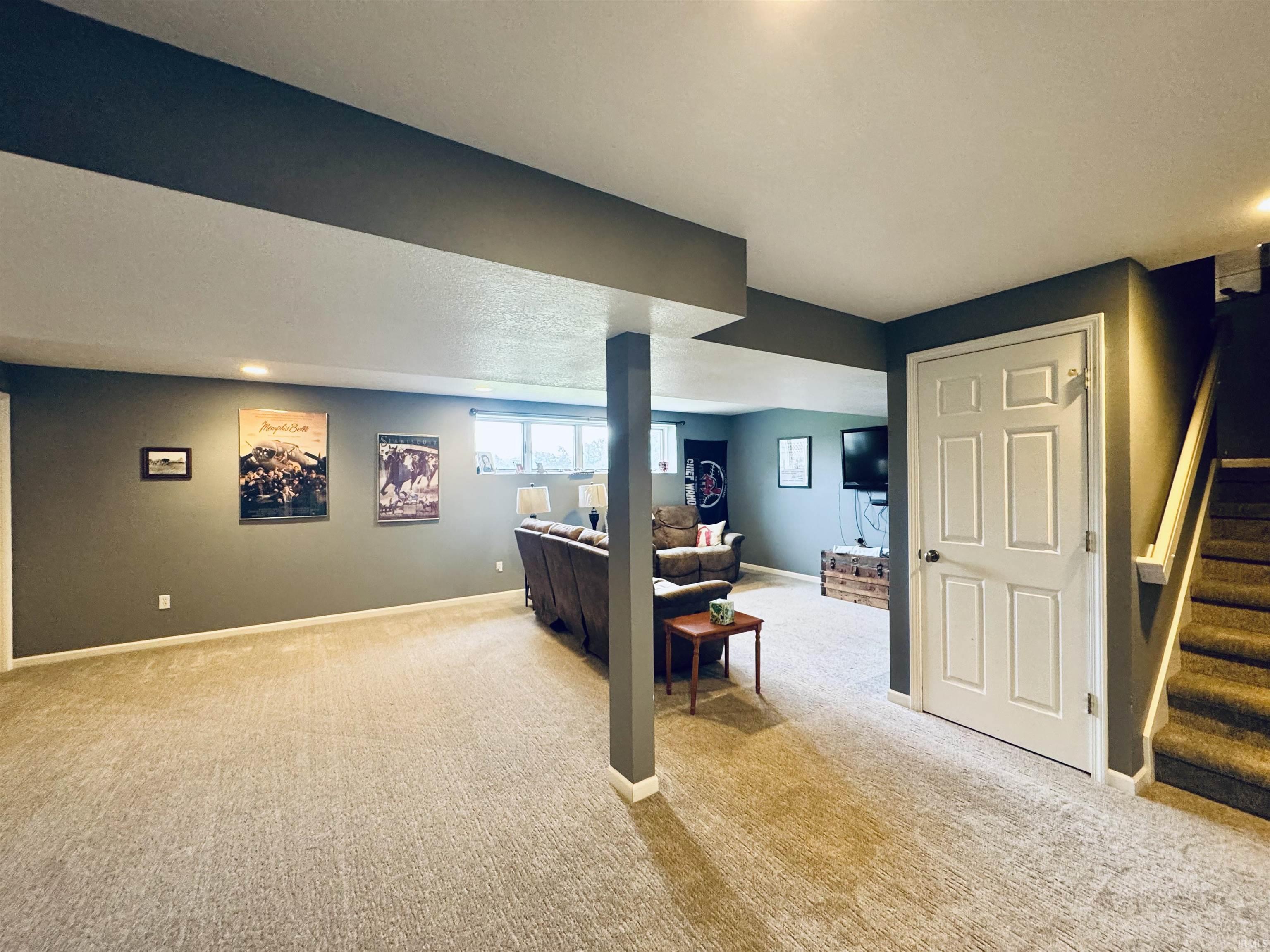 Carpeted flooring throughout, recessed lighting, white paneled interior door, and a staircase with carpeted treads